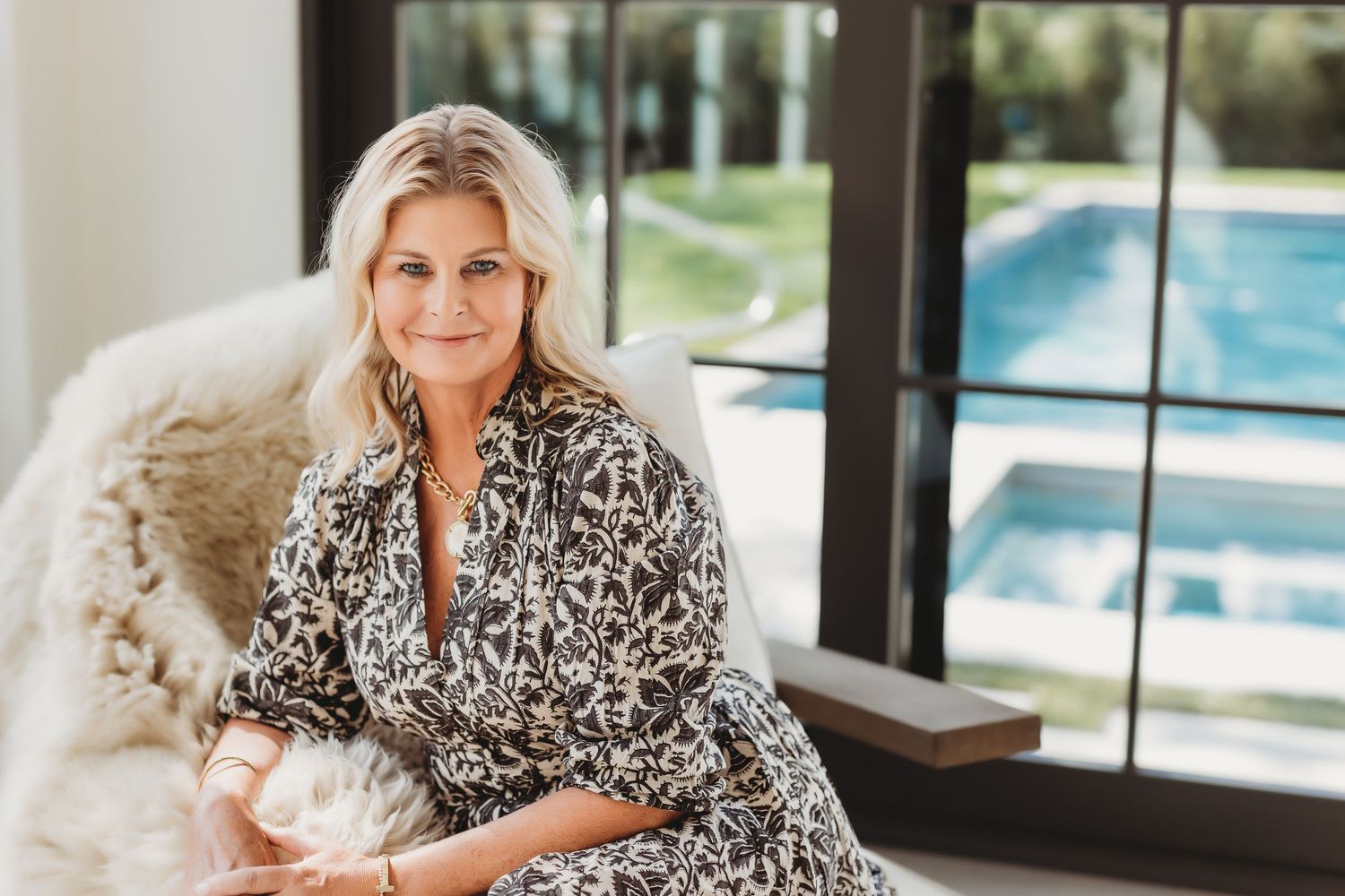 Casual lifestyle photo featuring someone in a black and white floral print dress near a swimming pool.