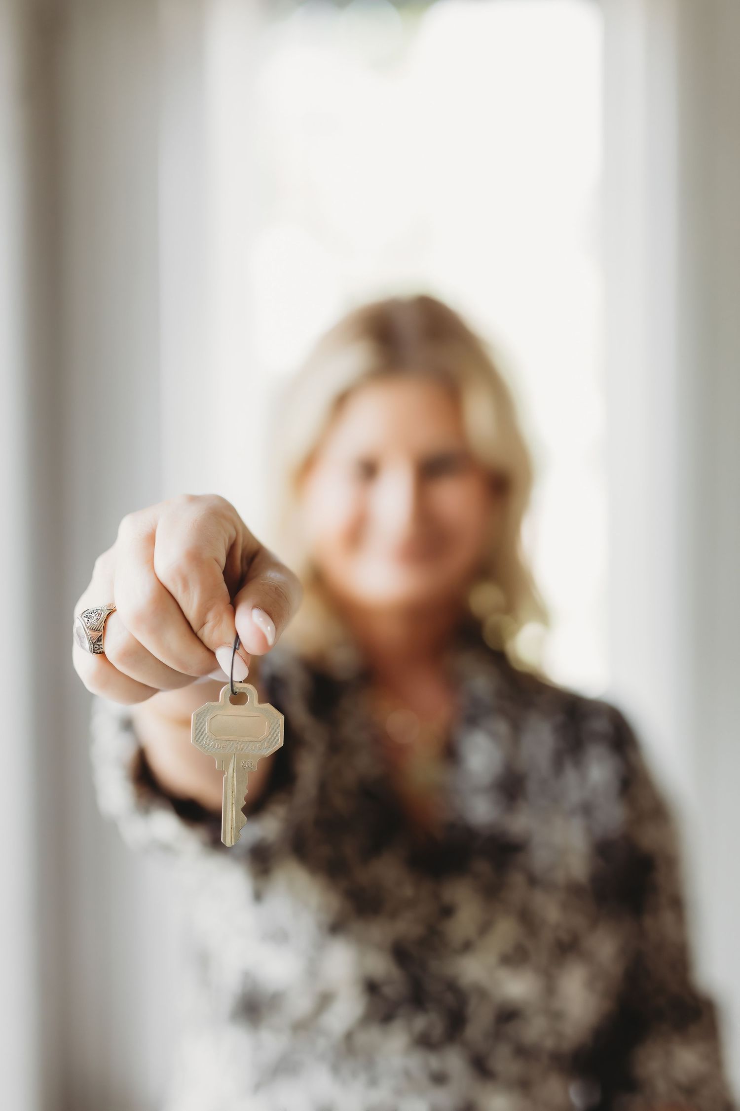 Person holding up keys in a bright interior space with windows.