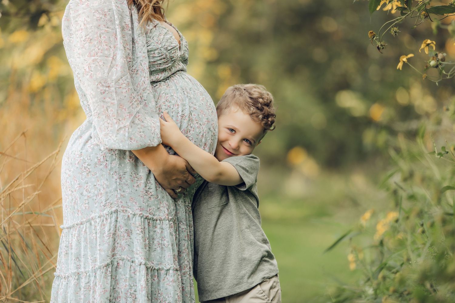 Tender outdoor family photography session in warm autumn light with soft neutral clothing and natural poses.