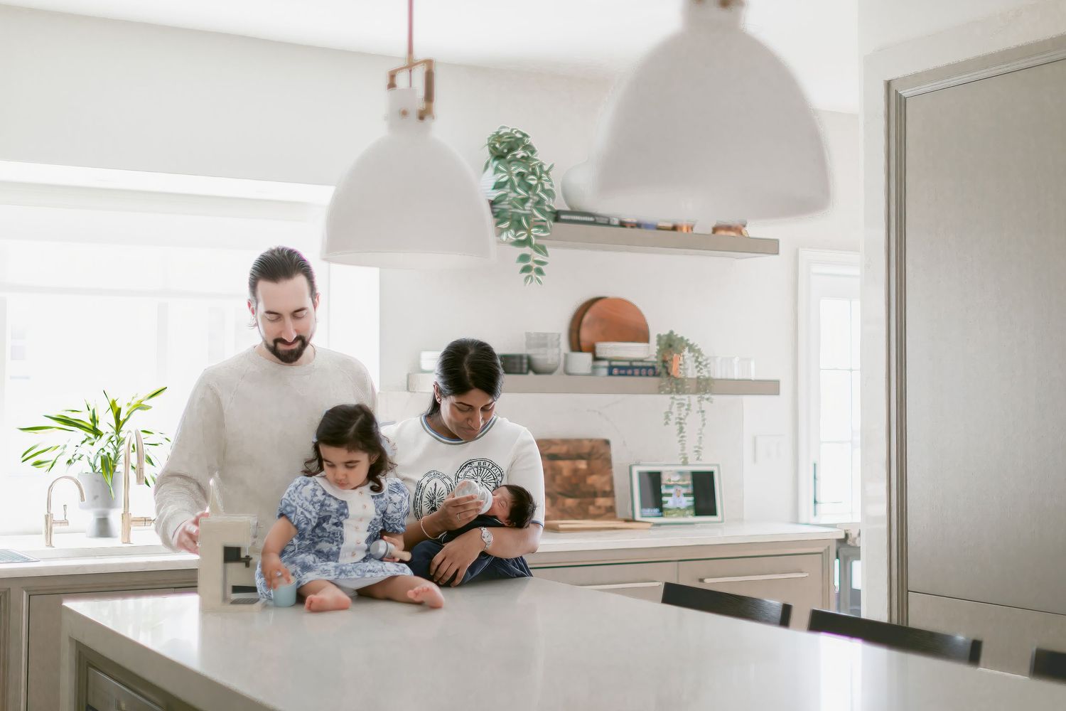 Family of three gathering in a bright modern kitchen, parents and child spending quality time together at a white island.