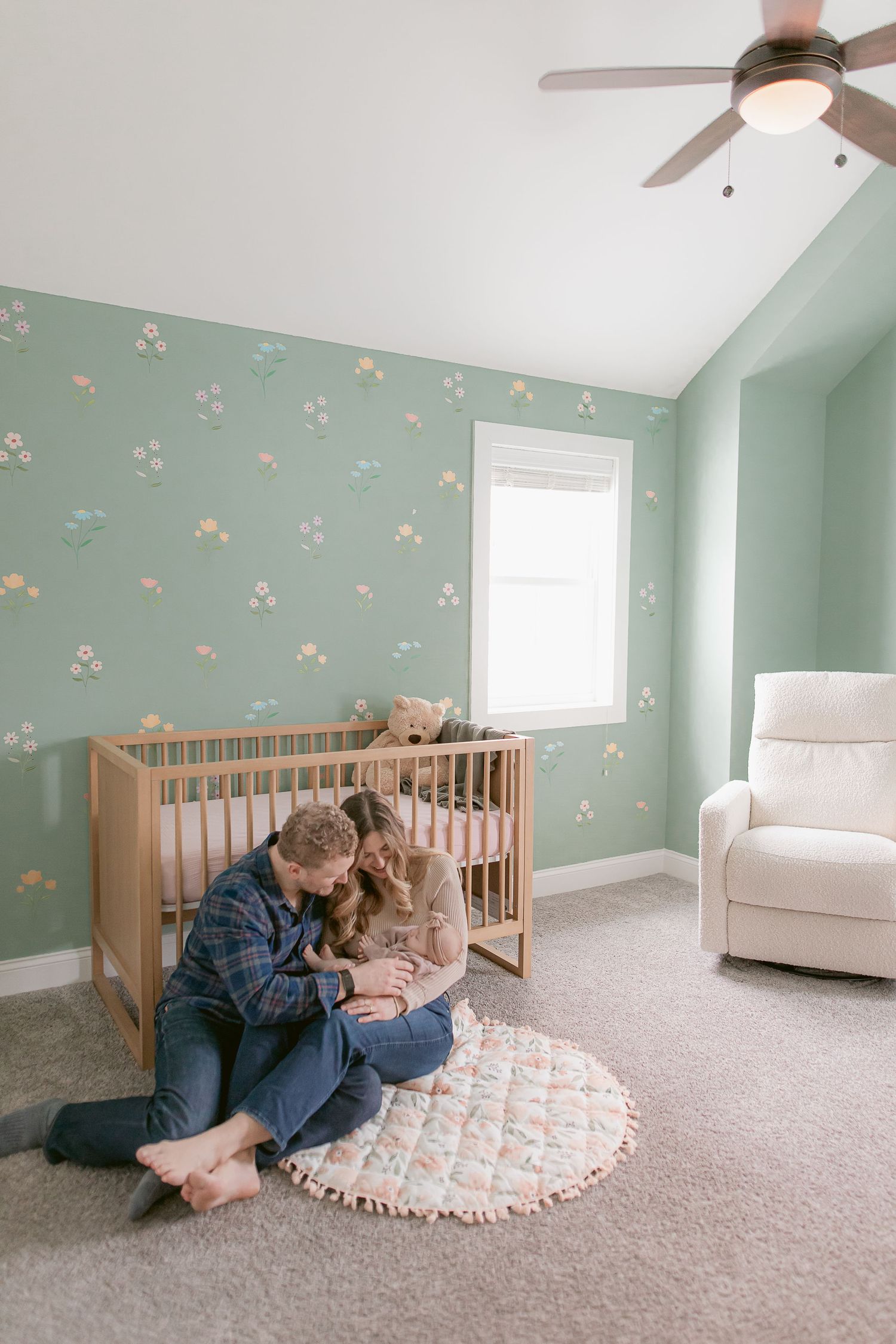 Cozy nursery scene with mint walls and wooden crib showing tender family moment.