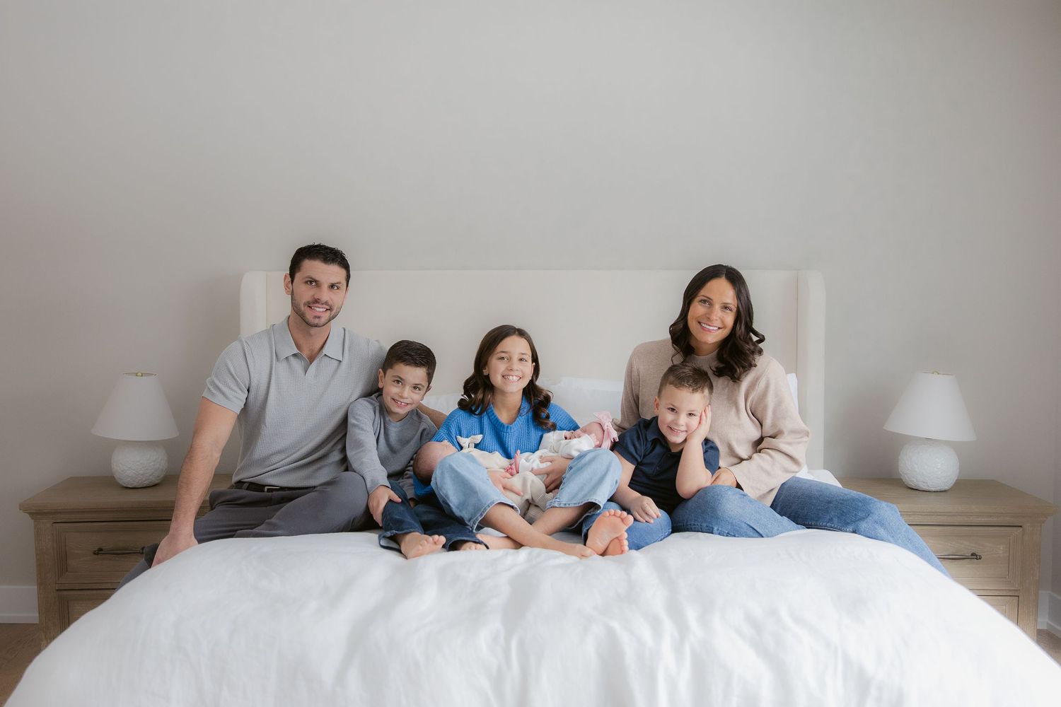 Family members lying together on a white bed in matching outfits creating a heartwarming scene.