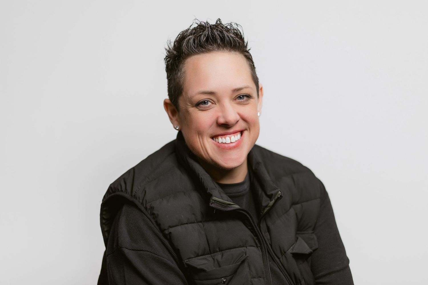 Professional portraits of person in black winter coat against light background.
