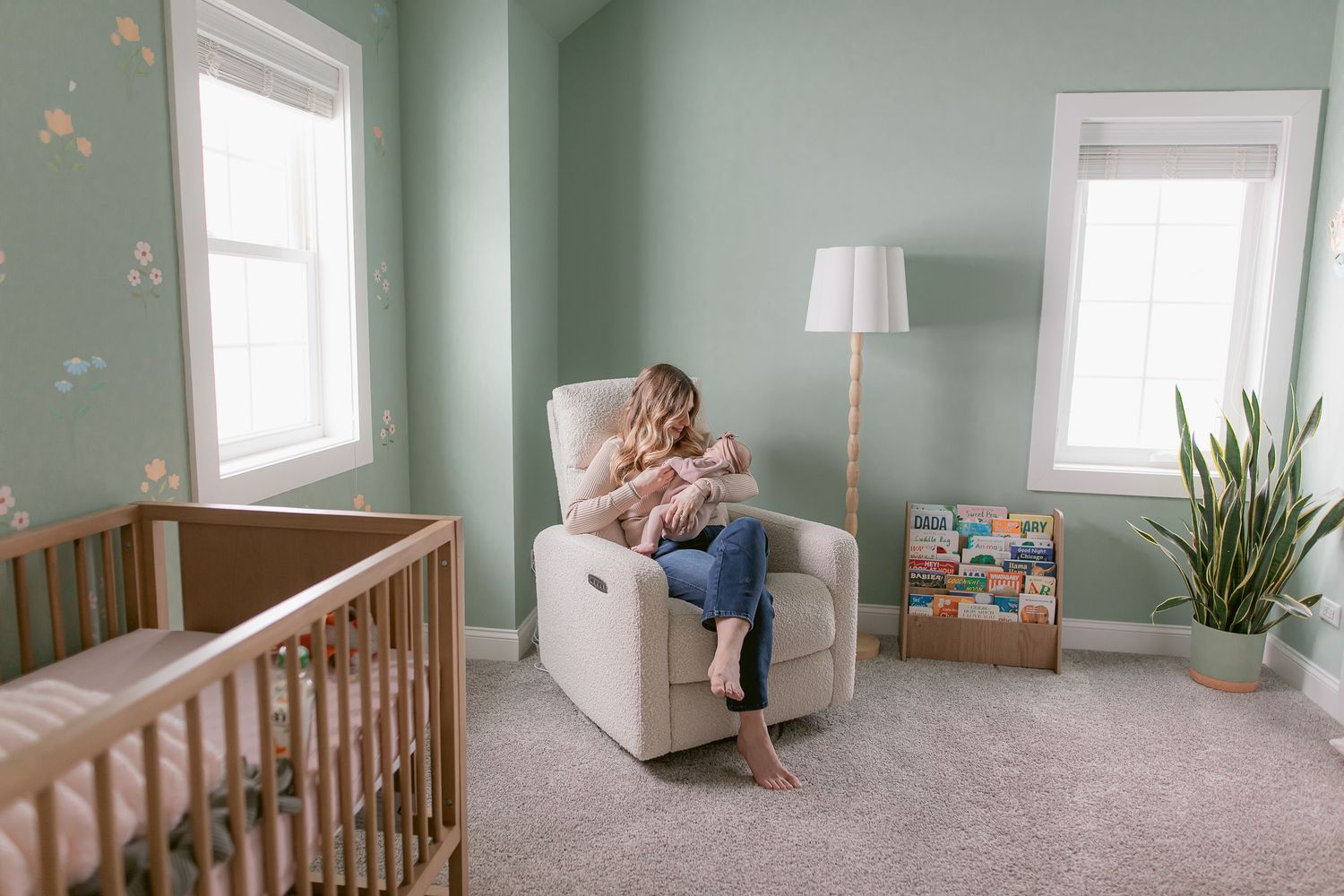 Nursery with mint green walls, wooden crib, and delicate floral wallpaper accents.