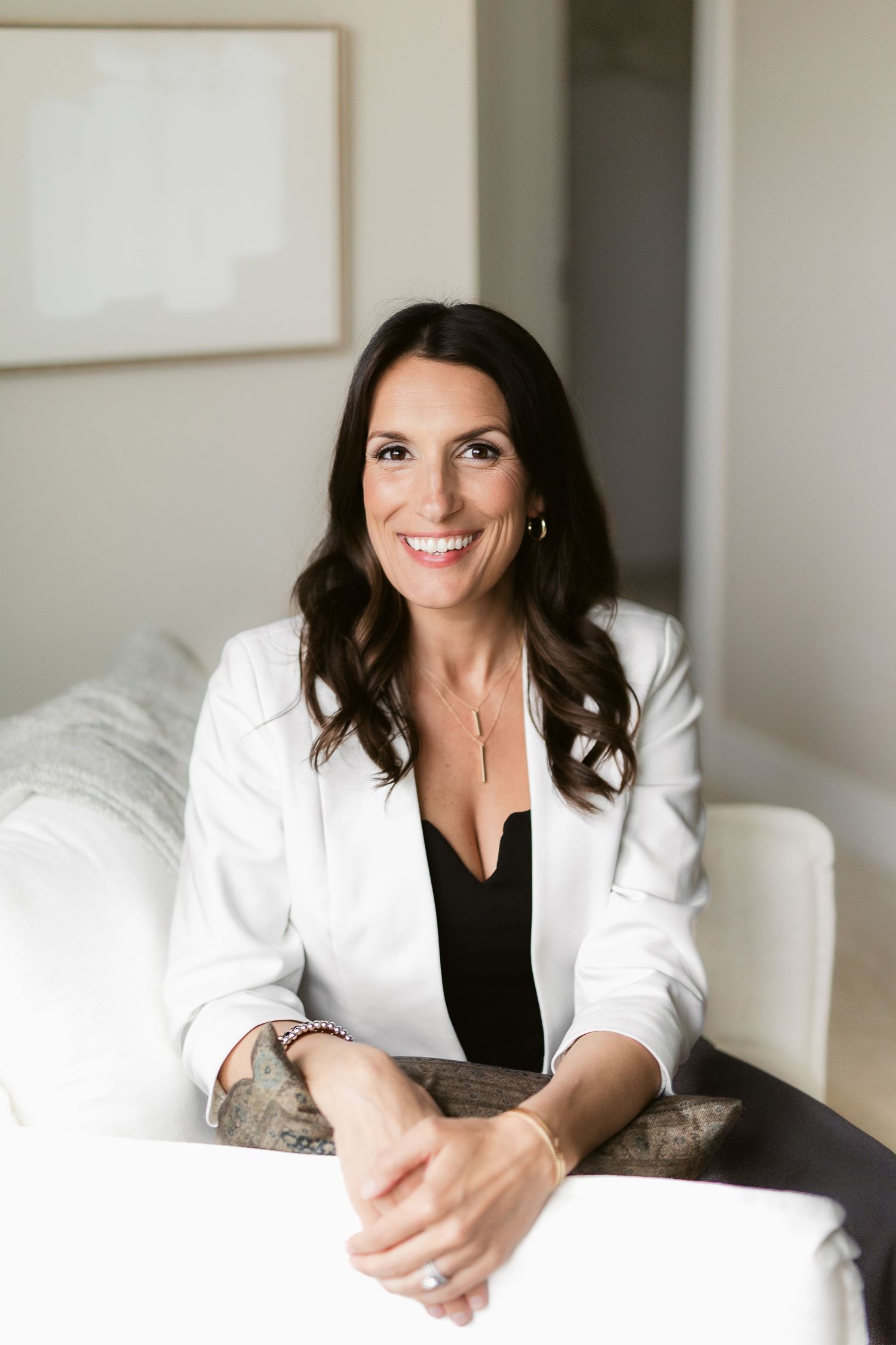 Professional portraits in white blazer against neutral backdrop with natural lighting.