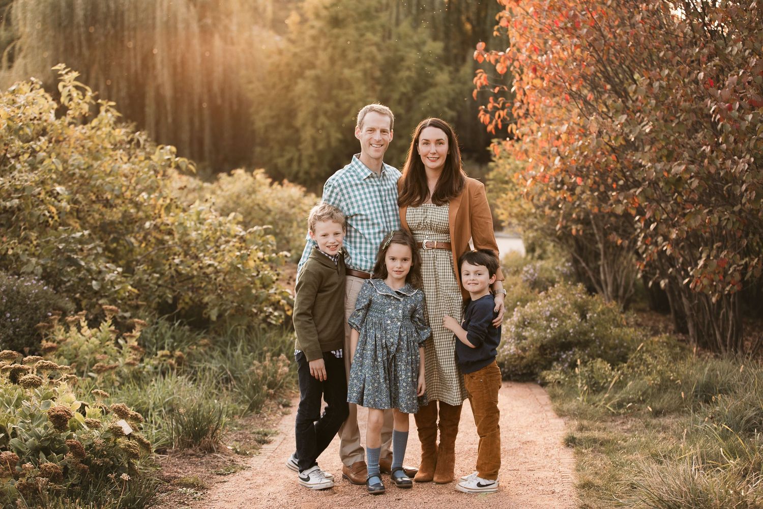 Family of five posing on autumn trail surrounded by fall colors.
