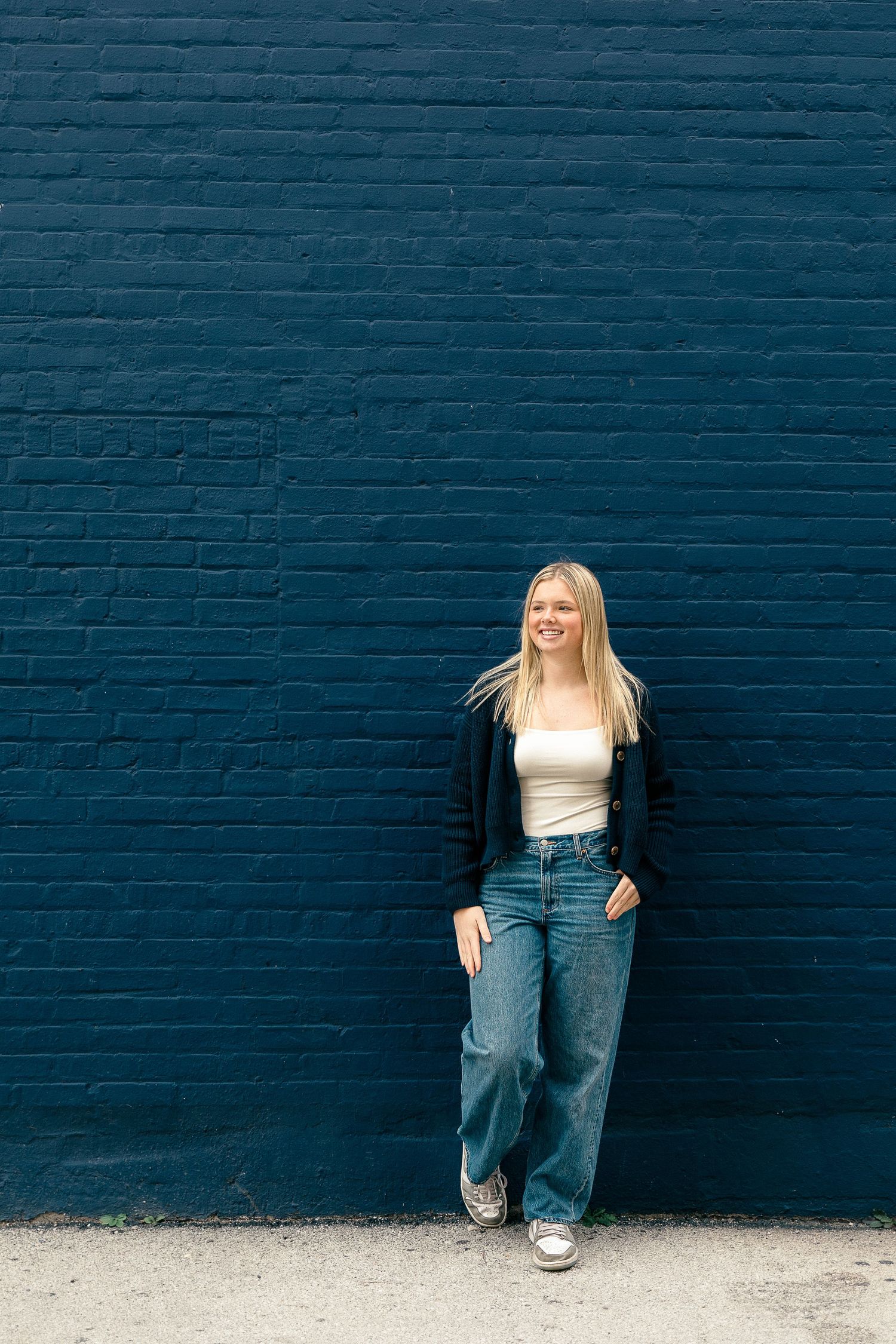 Casual portrait against a navy blue brick wall showing dynamic movement.