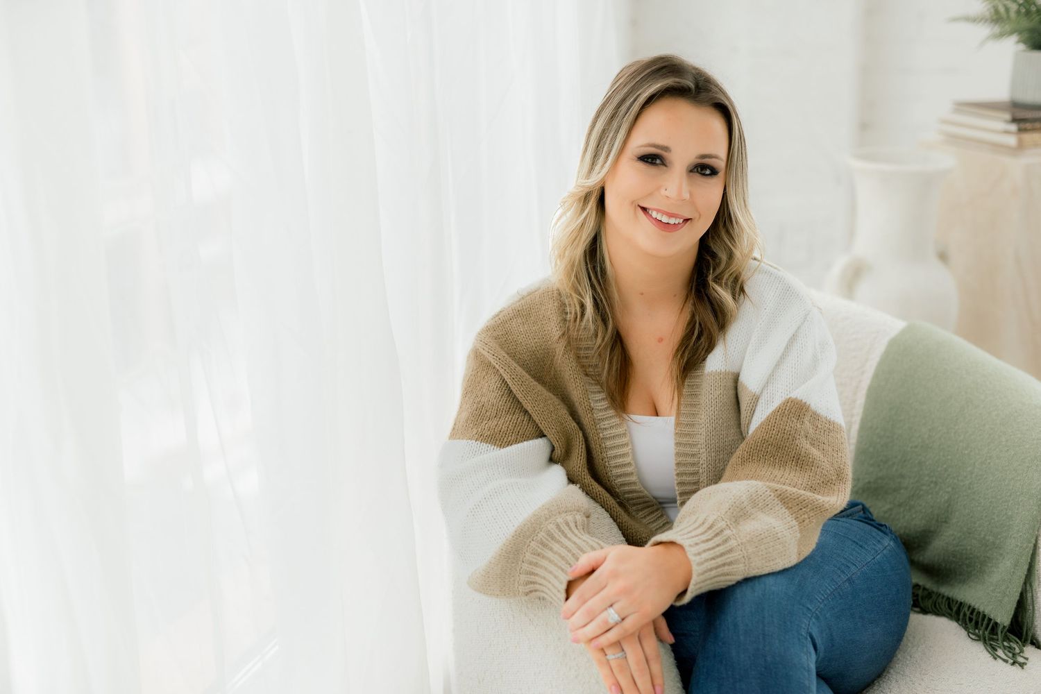 Person in casual beige sweater relaxes on studio furniture.