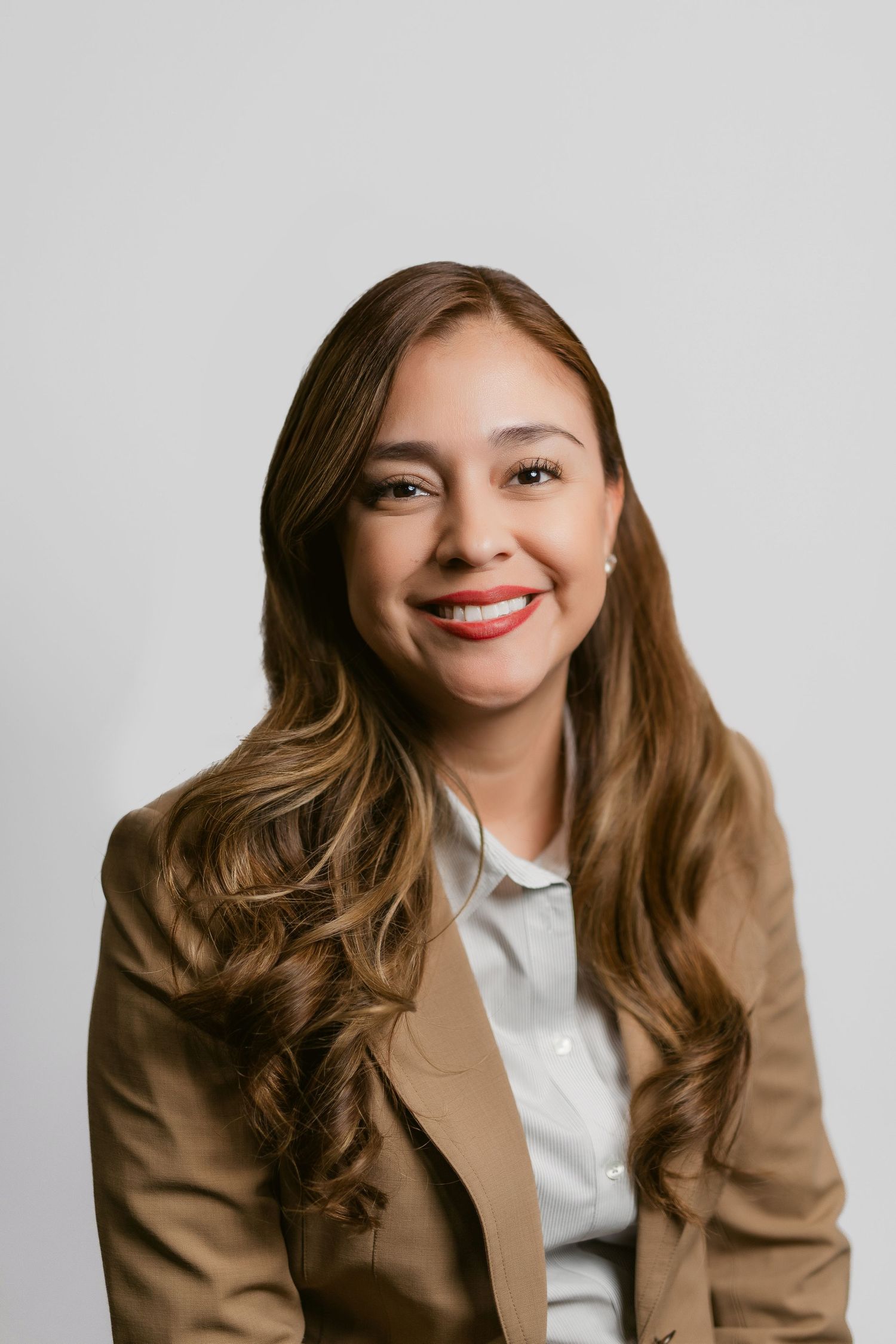 Professional headshots of a person in a brown blazer and white shirt against a light background.
