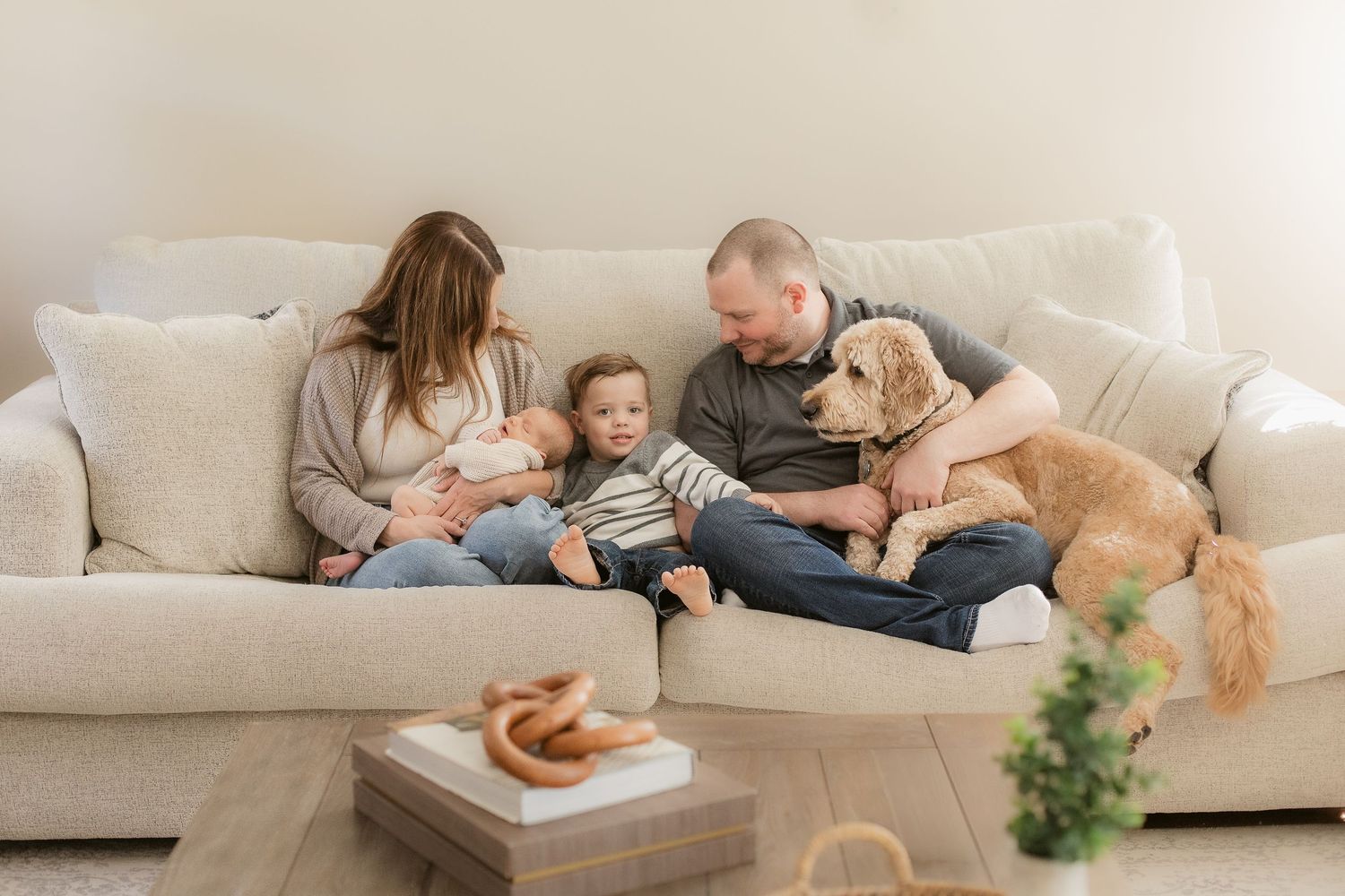 Candid family lifestyle session on beige couch showing relaxed at-home moments together.