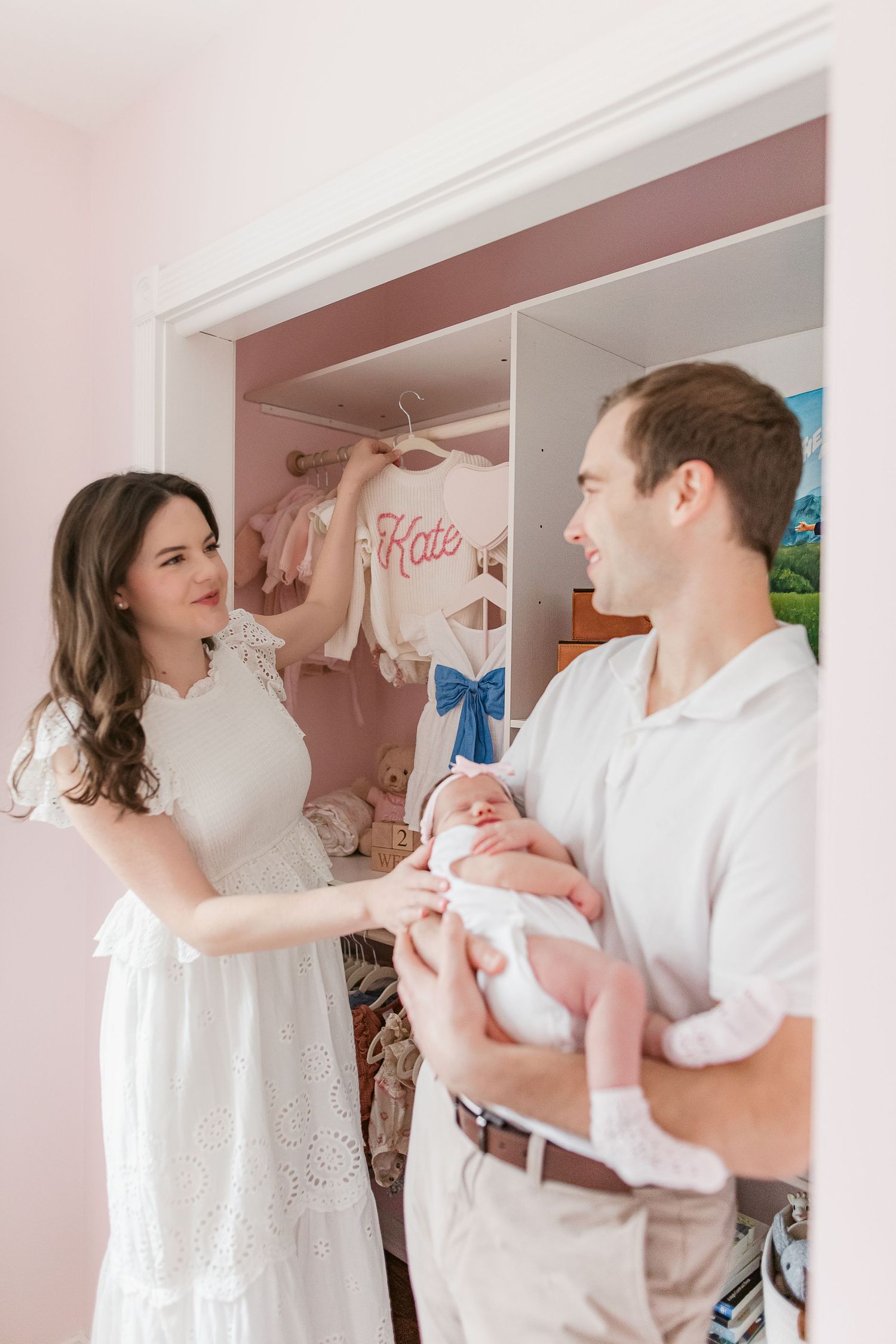 Sweet family interaction in a pink-accented nursery with white decor.