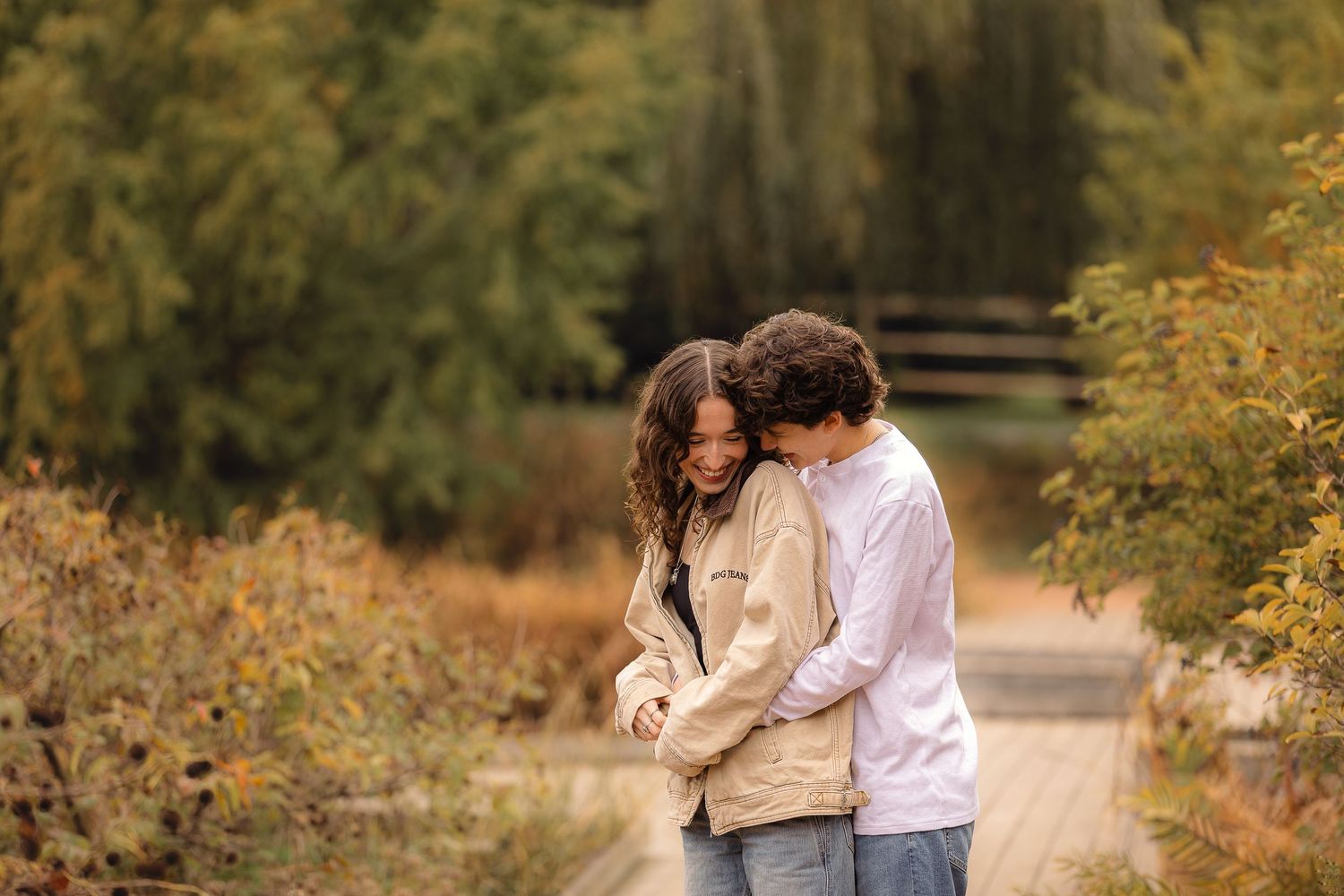 Couple walking hand in hand through a scenic autumn park with golden trees.