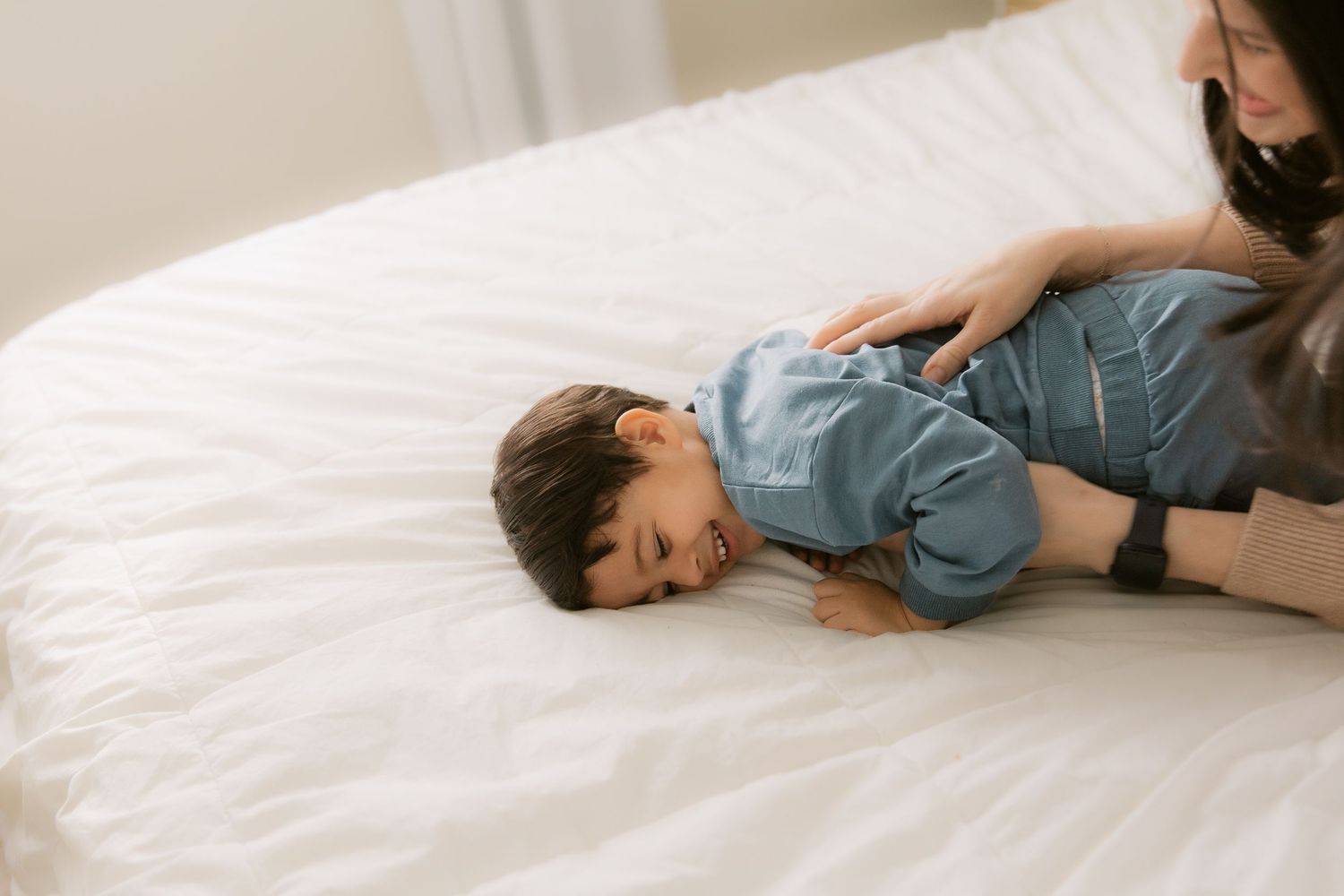 Person in blue shirt lying on white bedding in a series of relaxed poses.