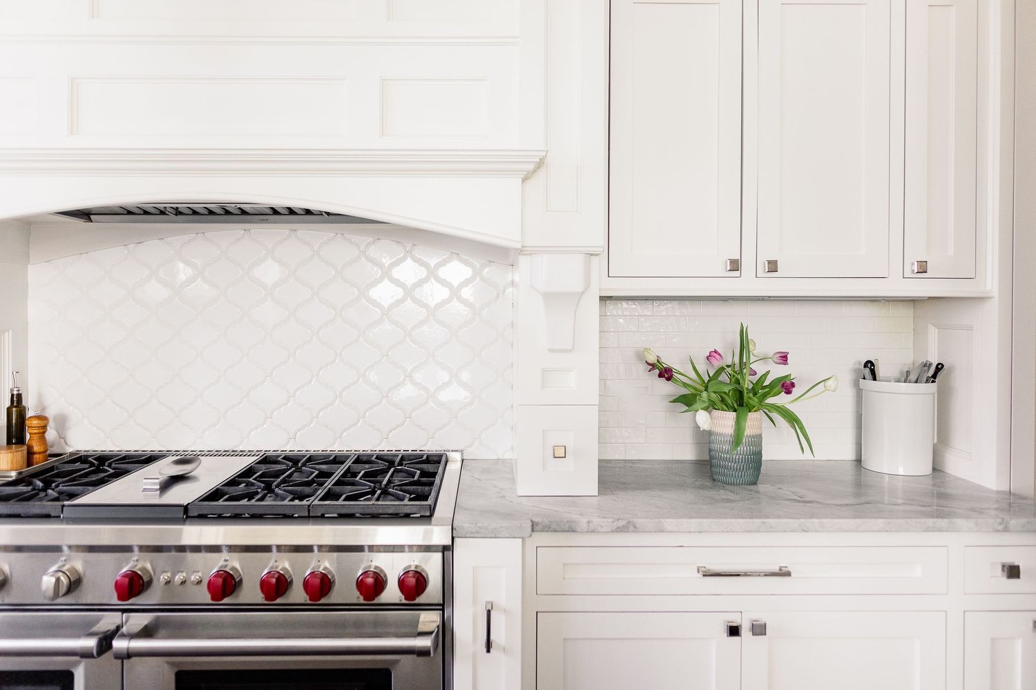 White kitchen with subway tile backsplash, stainless steel range, quartz countertops and white cabinets.