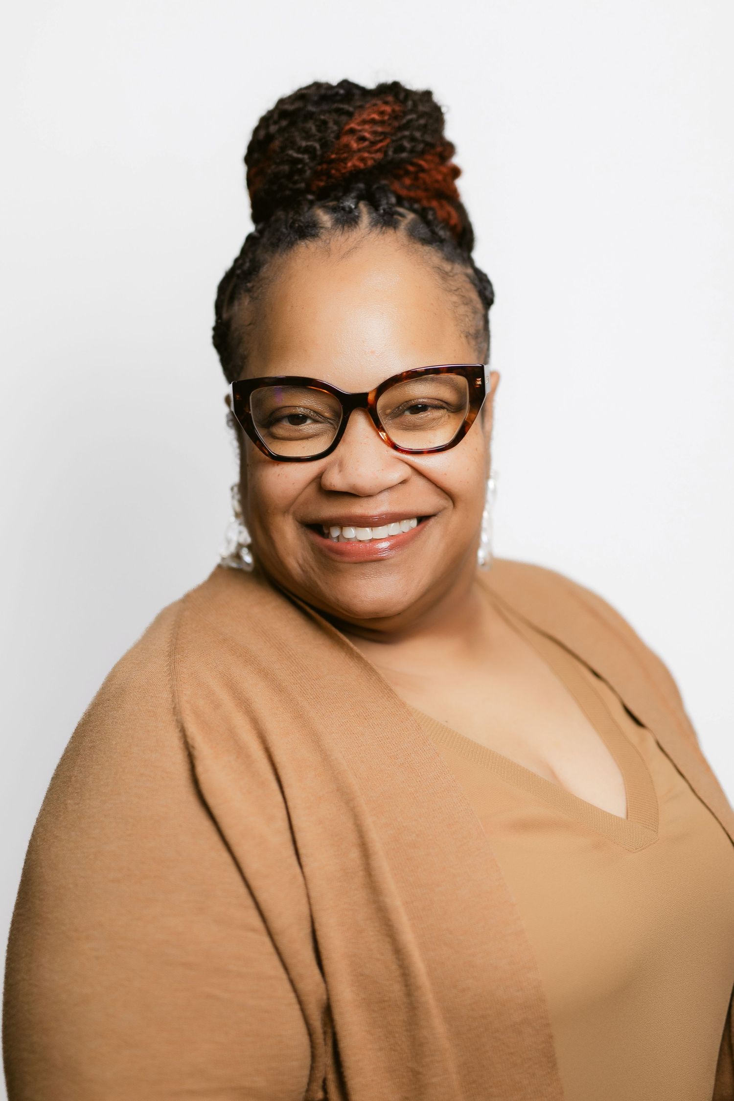 Professional headshots of a person wearing glasses and tan cardigan against white background.