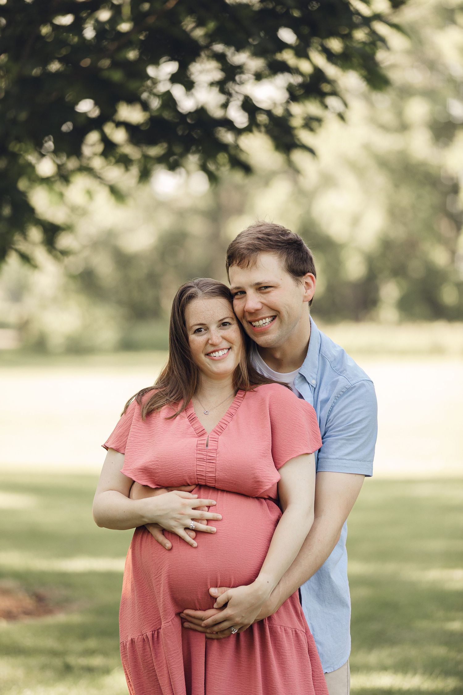 A couple shares an intimate moment outdoors during a maternity photoshoot.