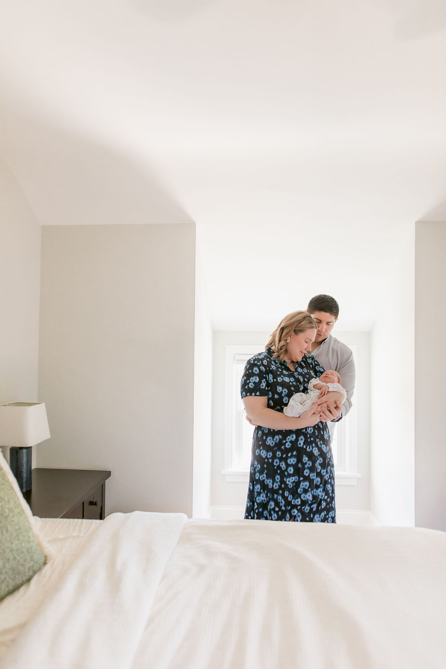 Tender moment in bright bedroom with floral dress and soft natural lighting.