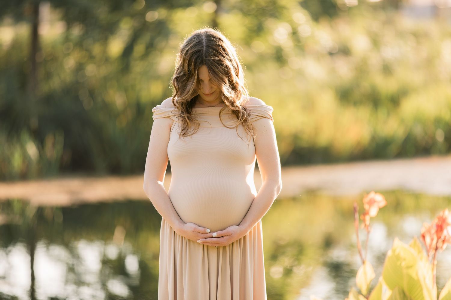 A peaceful maternity portrait with soft lighting and natural outdoor elements.