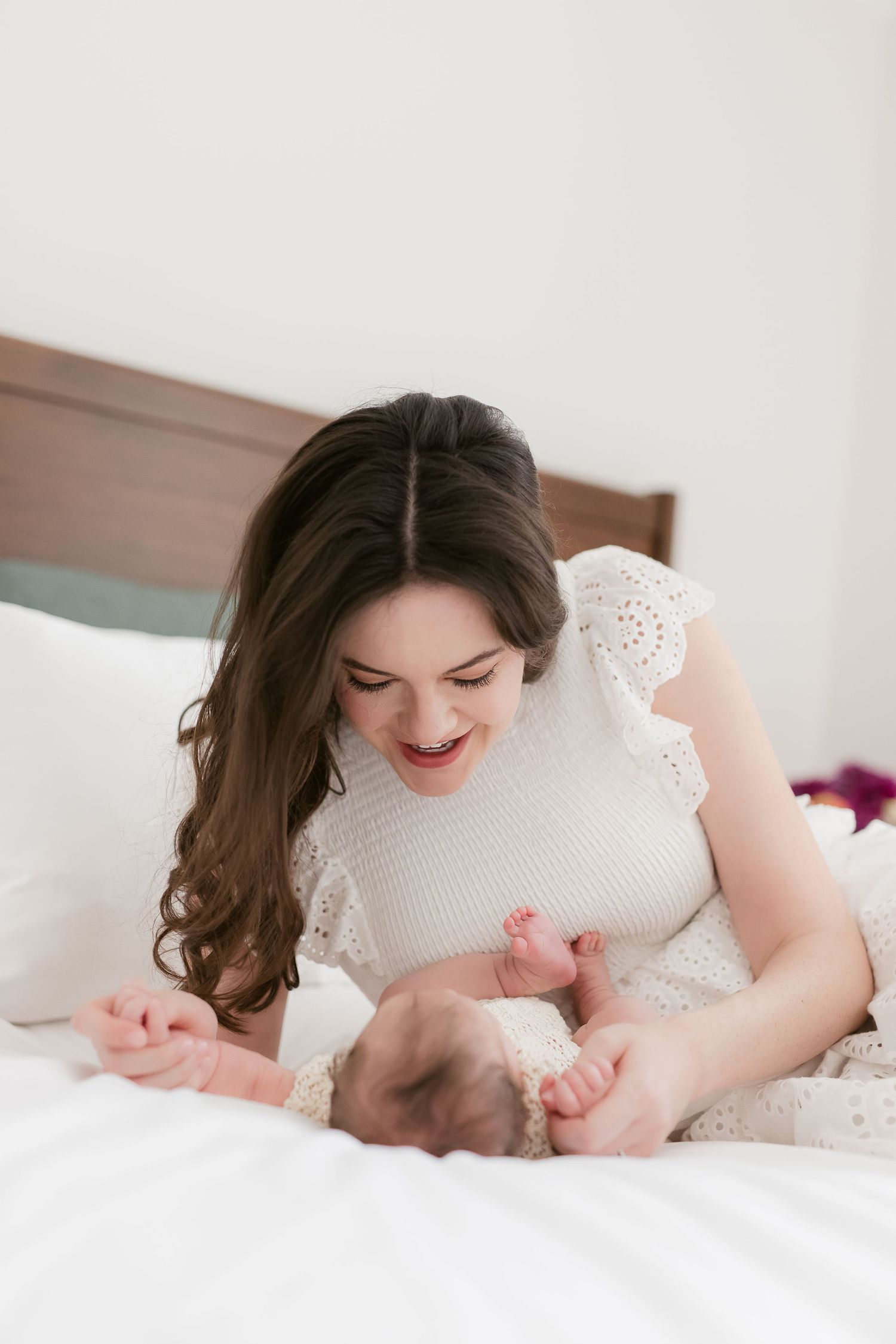Tender moment captured on white bedding in natural light.
