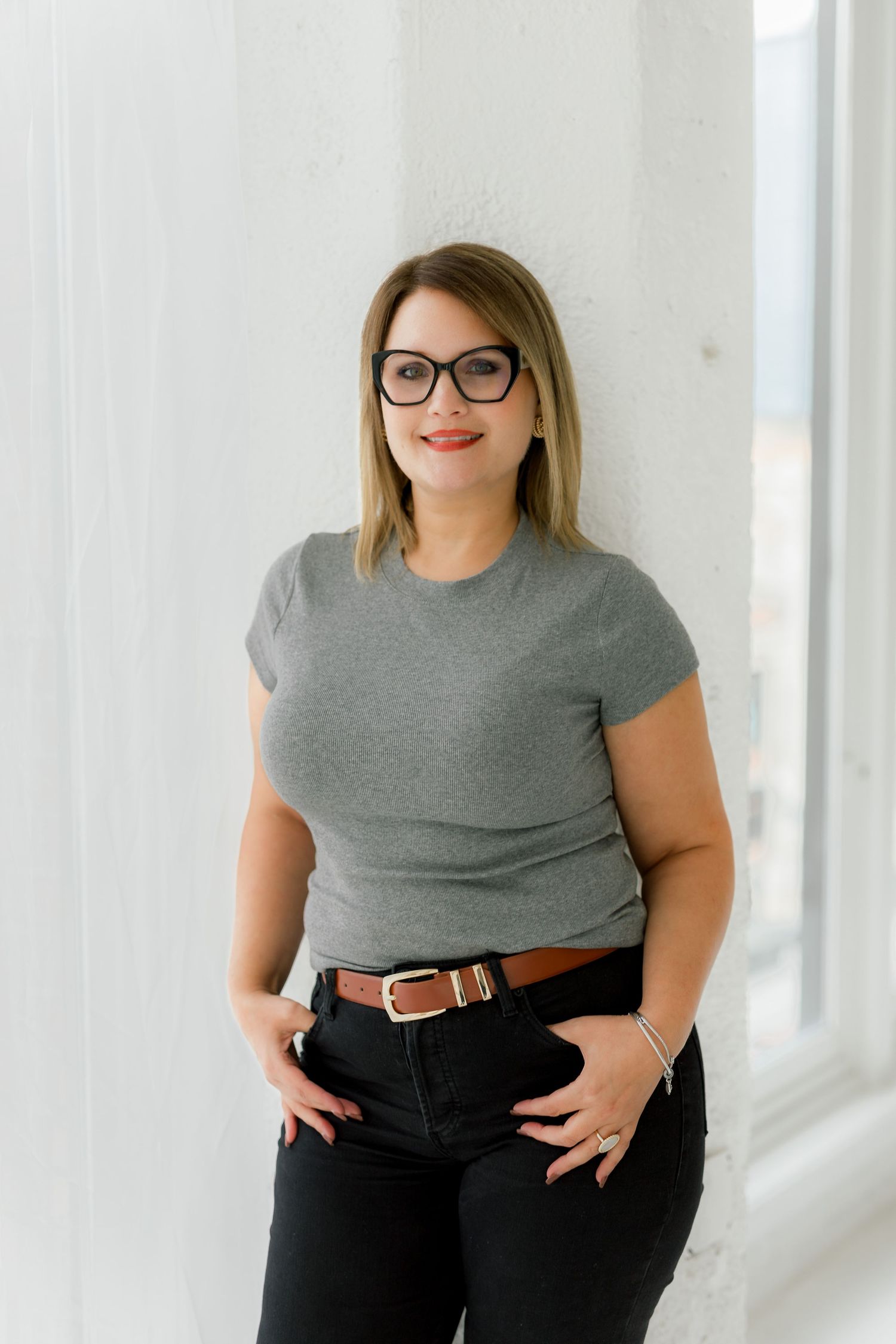 Business casual portrait in gray t-shirt and black jeans with glasses.