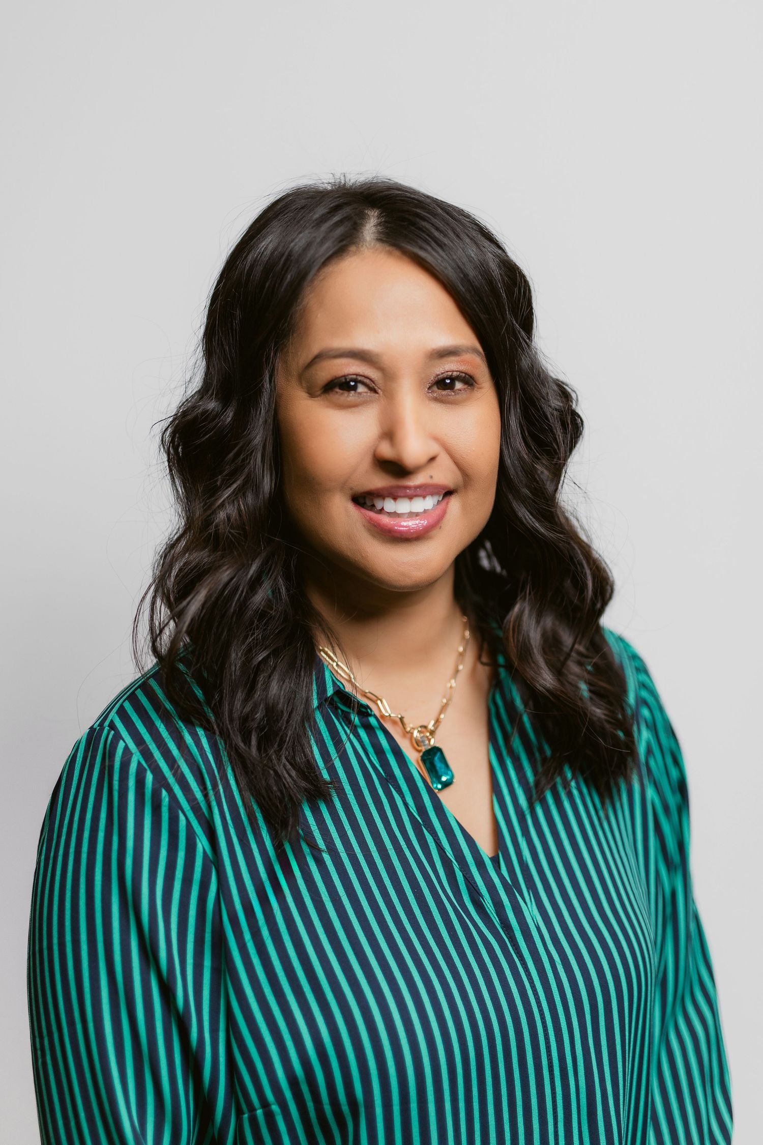 Professional headshots of person in striped teal blouse against white background.
