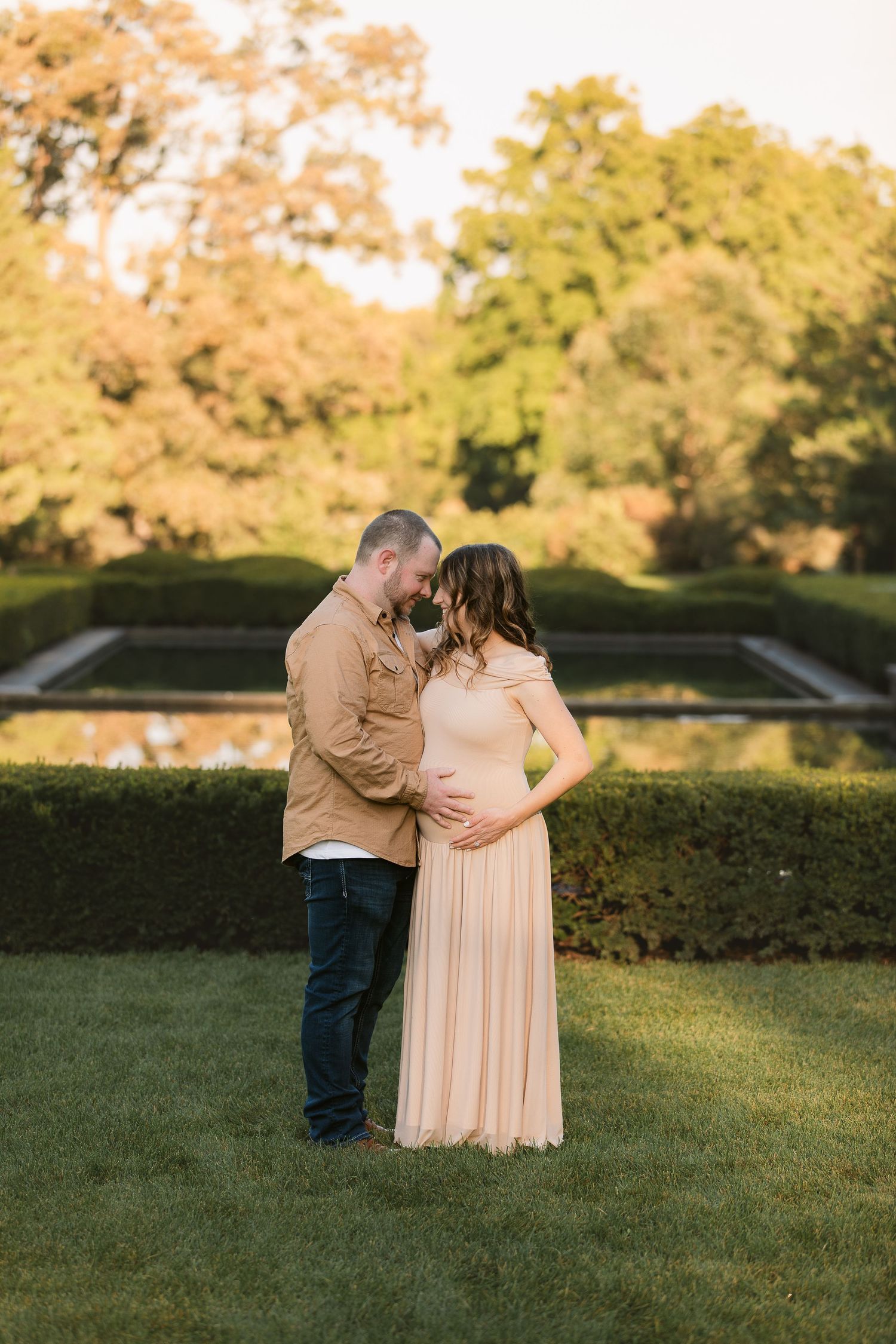 A maternity photoshoot in a peaceful garden setting during golden hour.