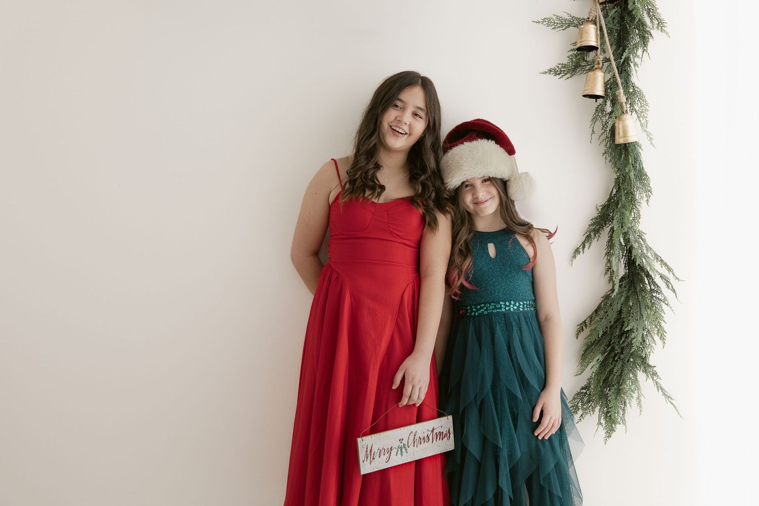 Holiday portrait setup with festive greenery and decorations against a white wall.