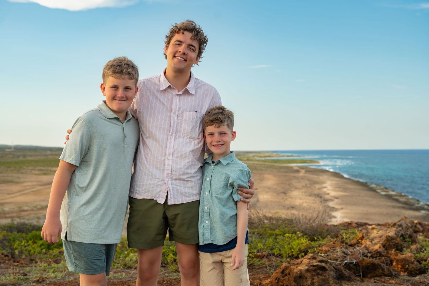 Family enjoying scenic coastal views during sunset at a hilltop location.