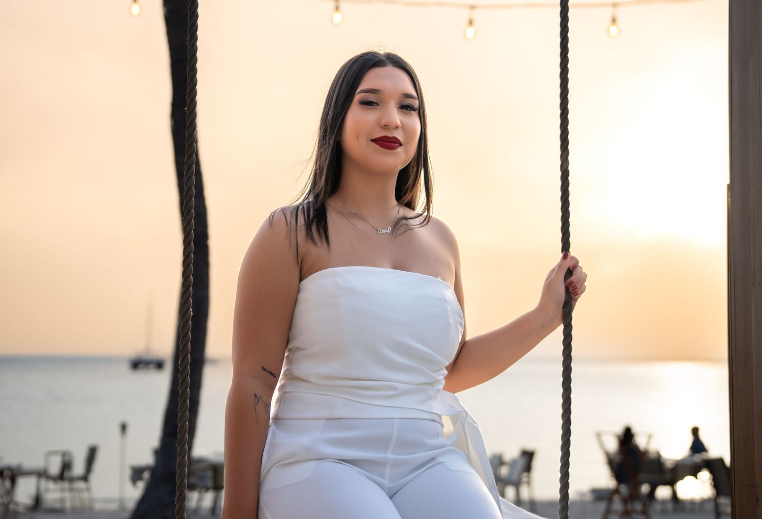Person in white dress posing against warm sunset lighting.