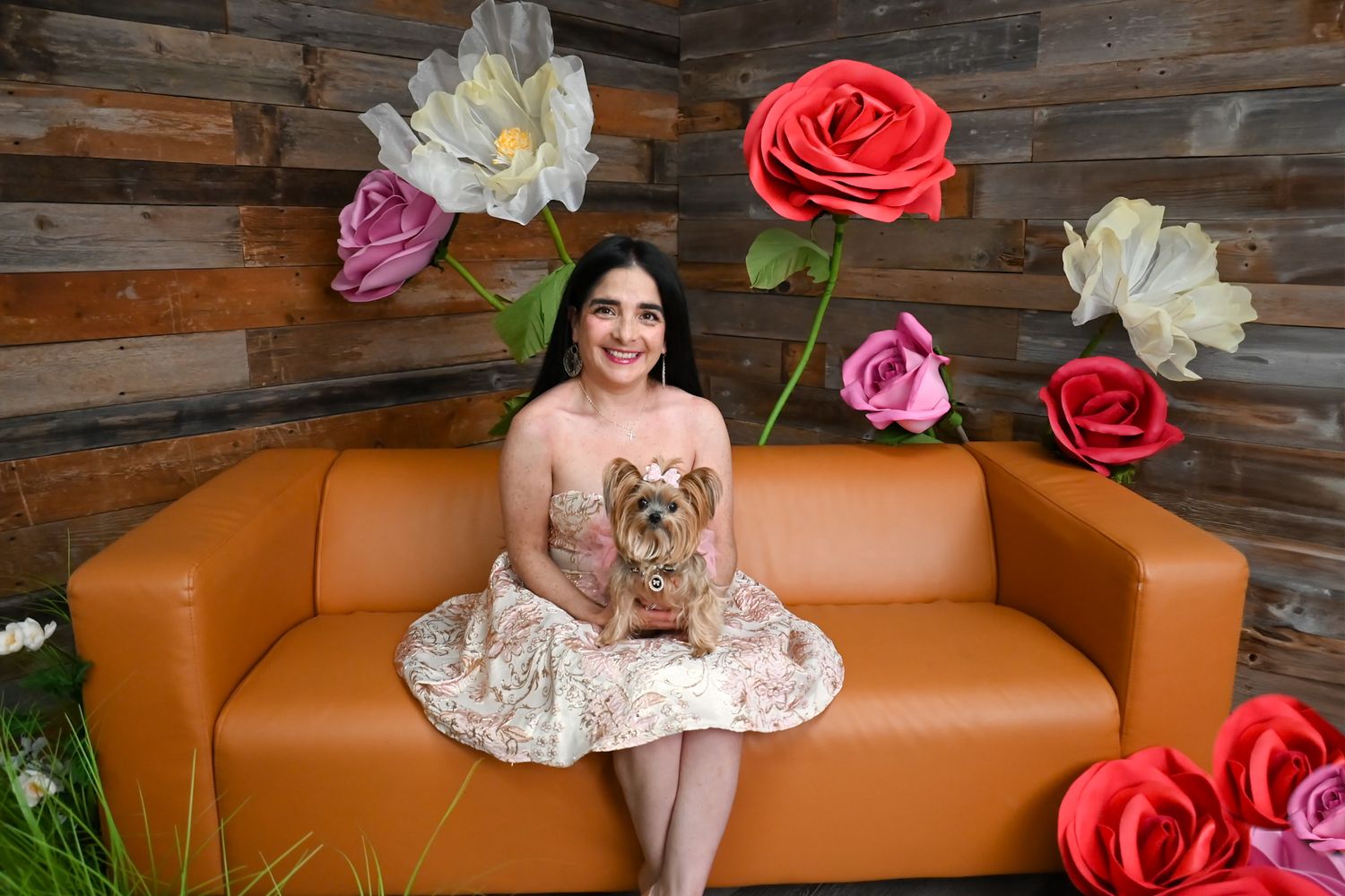 Orange leather couch against wooden wall with decorative floral arrangements.