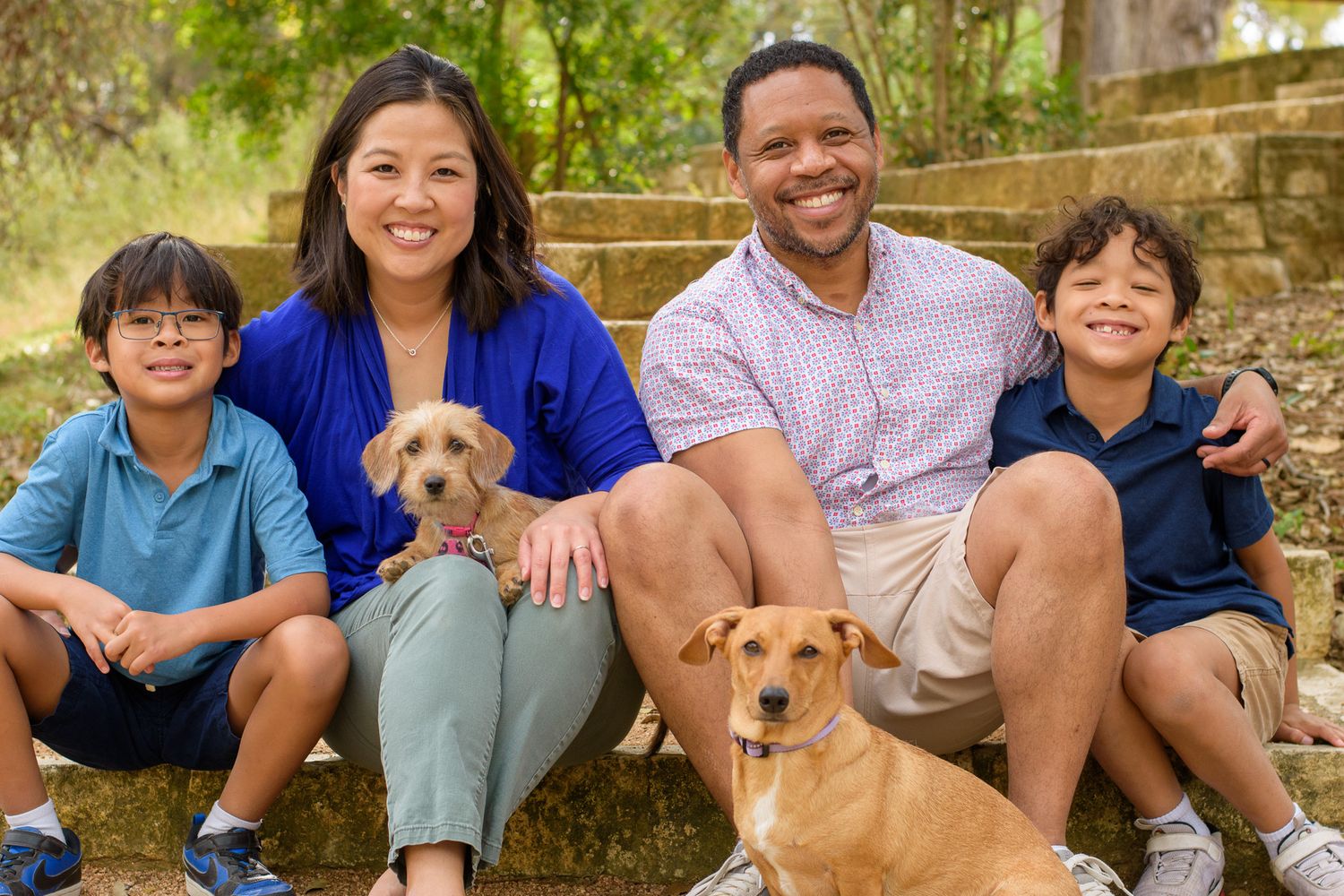 A family and their golden retriever pose together outdoors for casual portraits.