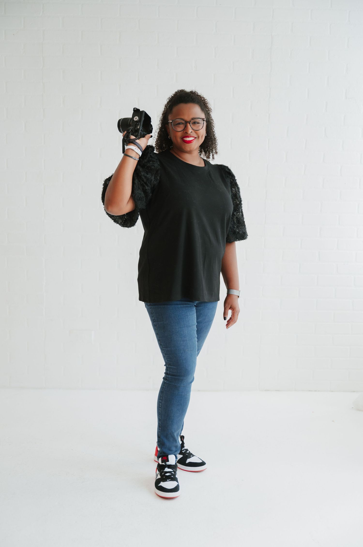 Person in black t-shirt and jeans posing confidently against white background.