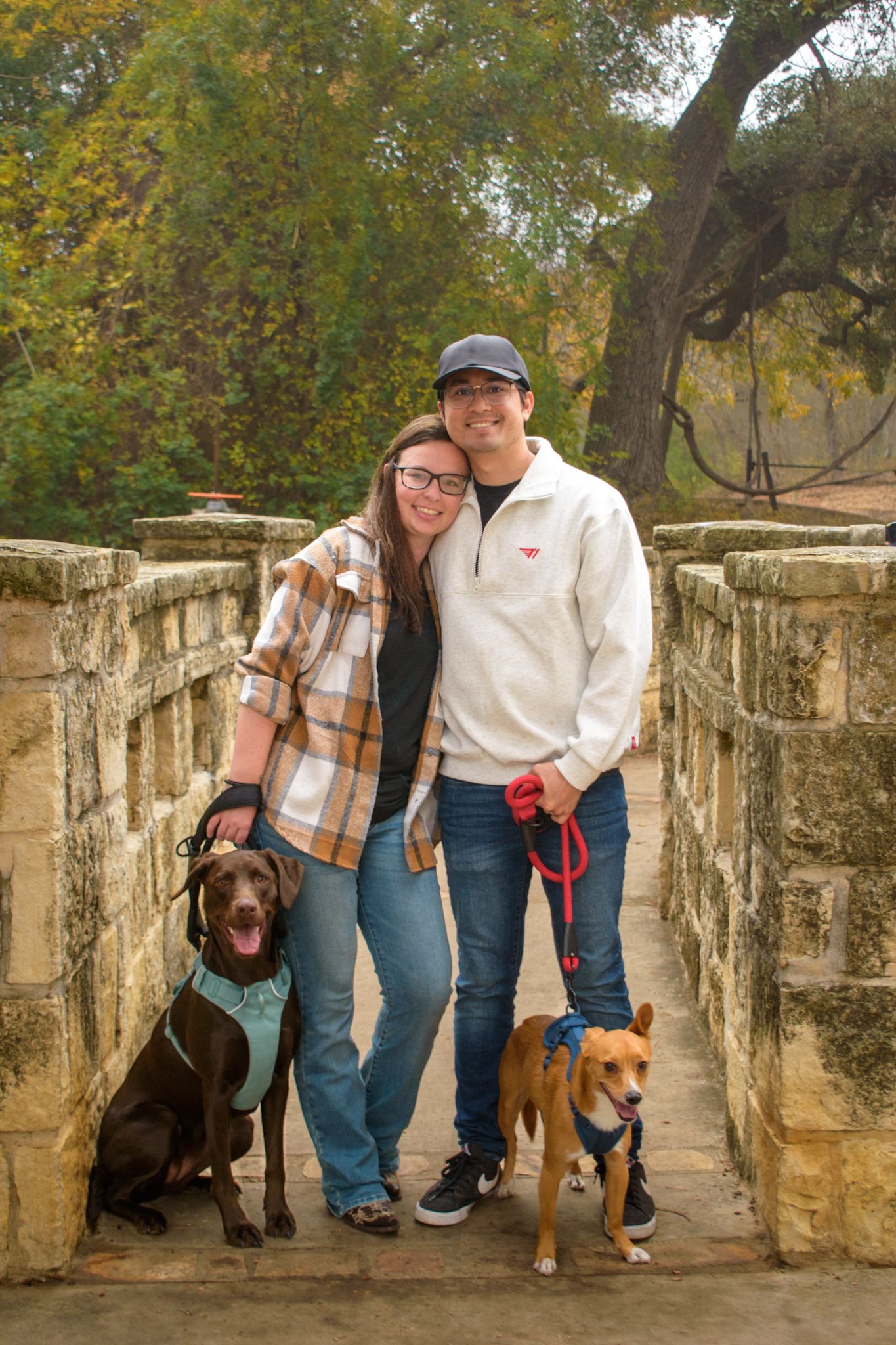 Casual outdoor portrait session with dogs on historic stone bridge path.