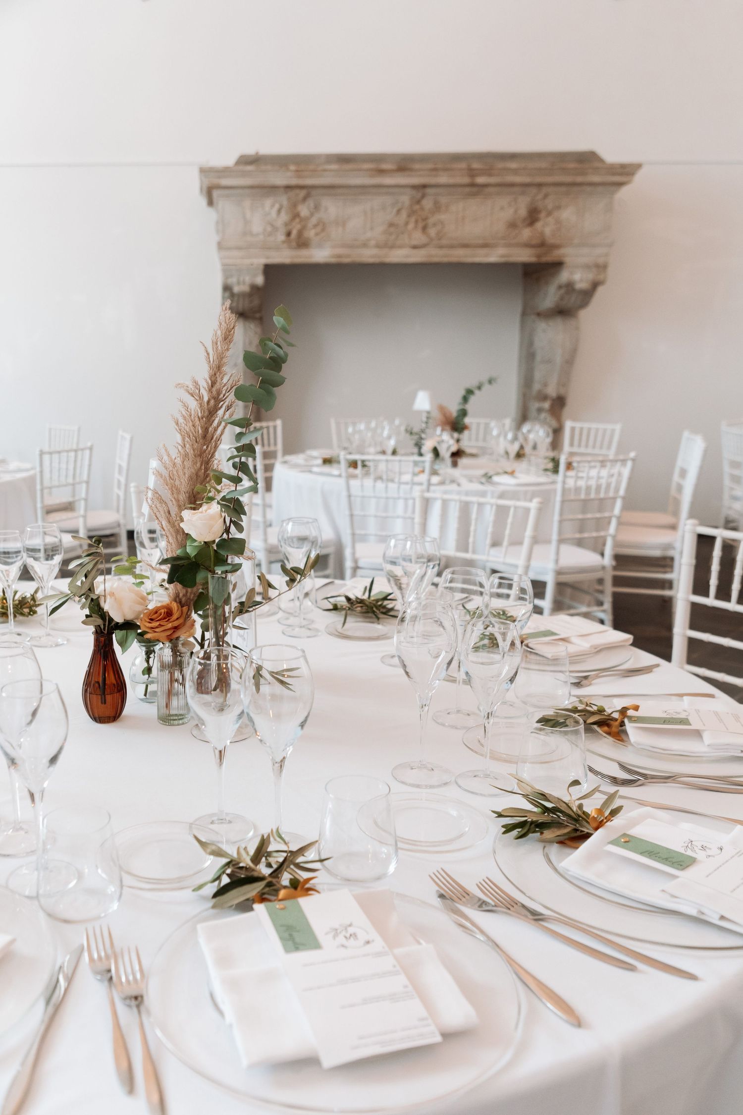 Elegant wedding reception table setting with floral centerpieces, white linens, and gold cutlery.