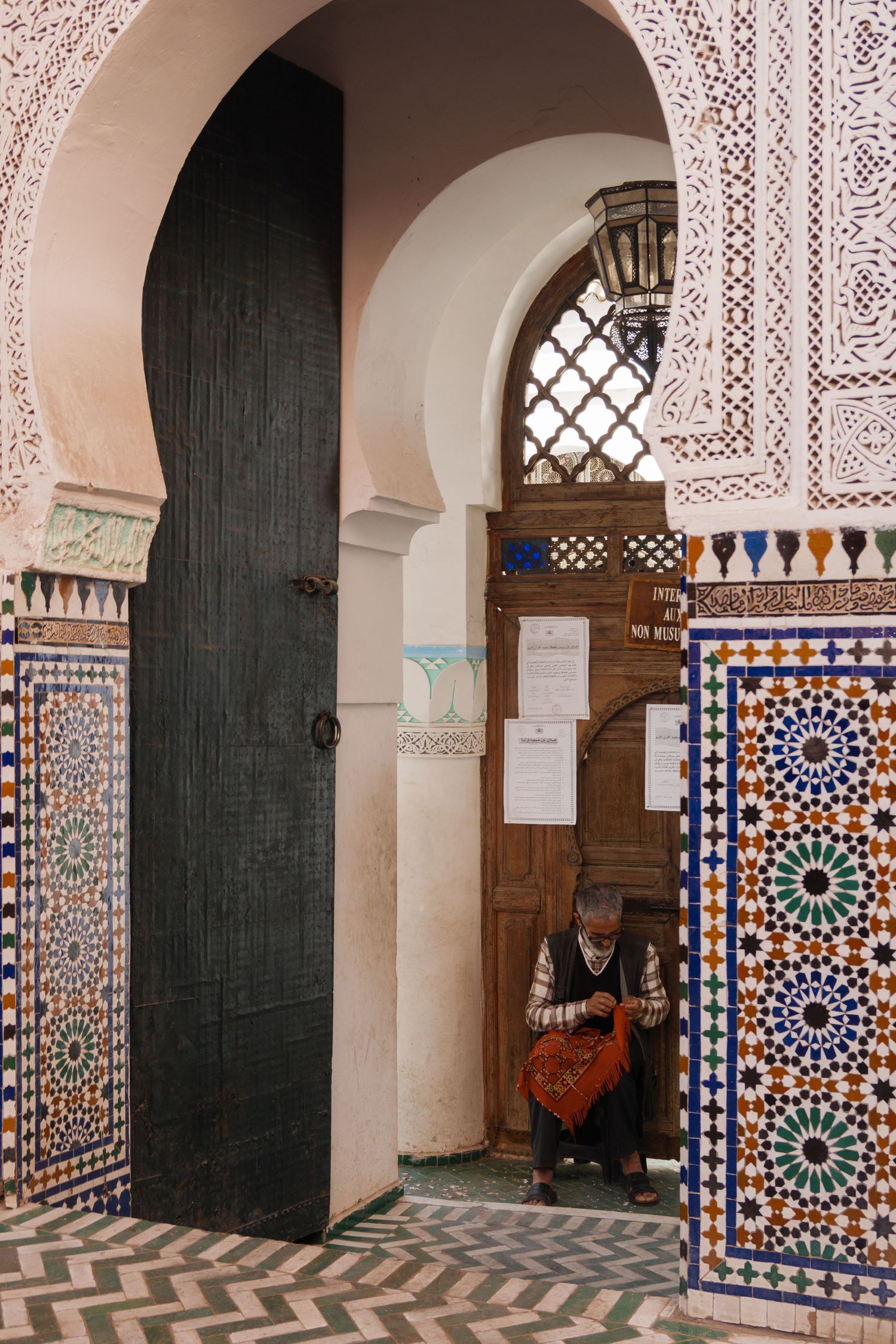 Ornate Moroccan mosque entrance with intricate zellige tilework and carved plasterwork archway.