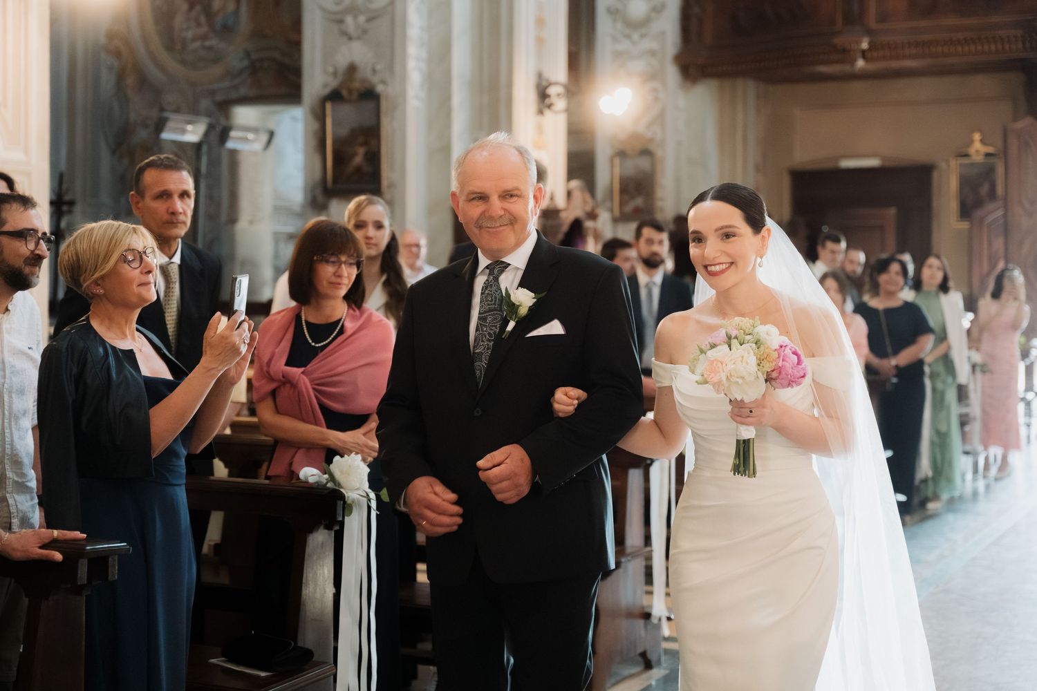 Bride walks down the church aisle with her father during a classic wedding ceremony.