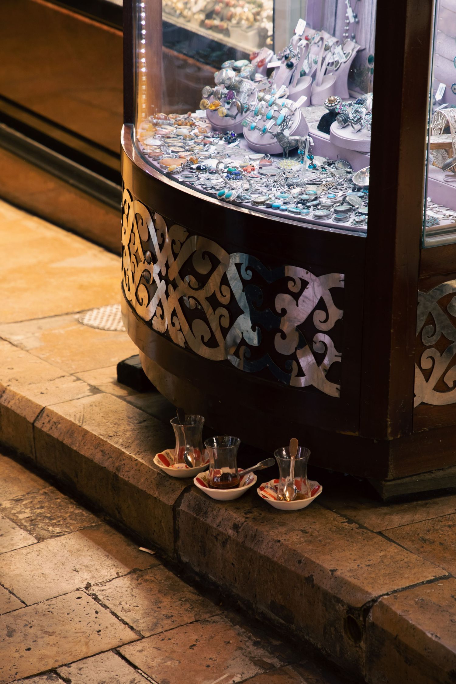 Traditional Turkish tea glasses and jewelry display case on cobblestone floor in Istanbul Grand Bazaar.