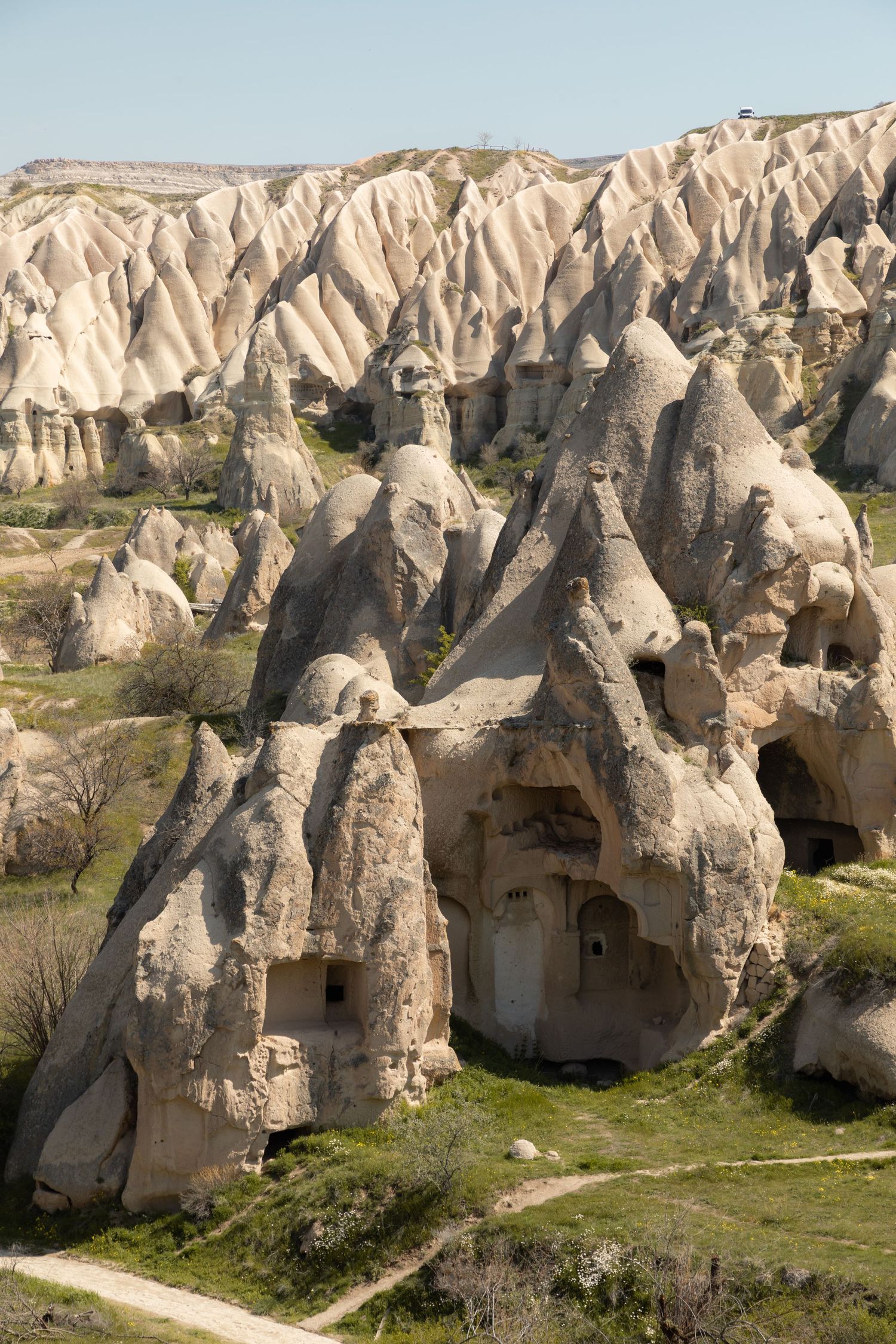 Tall cone-shaped fairy chimney rock formations with carved cave dwellings in Cappadocia's volcanic landscape.