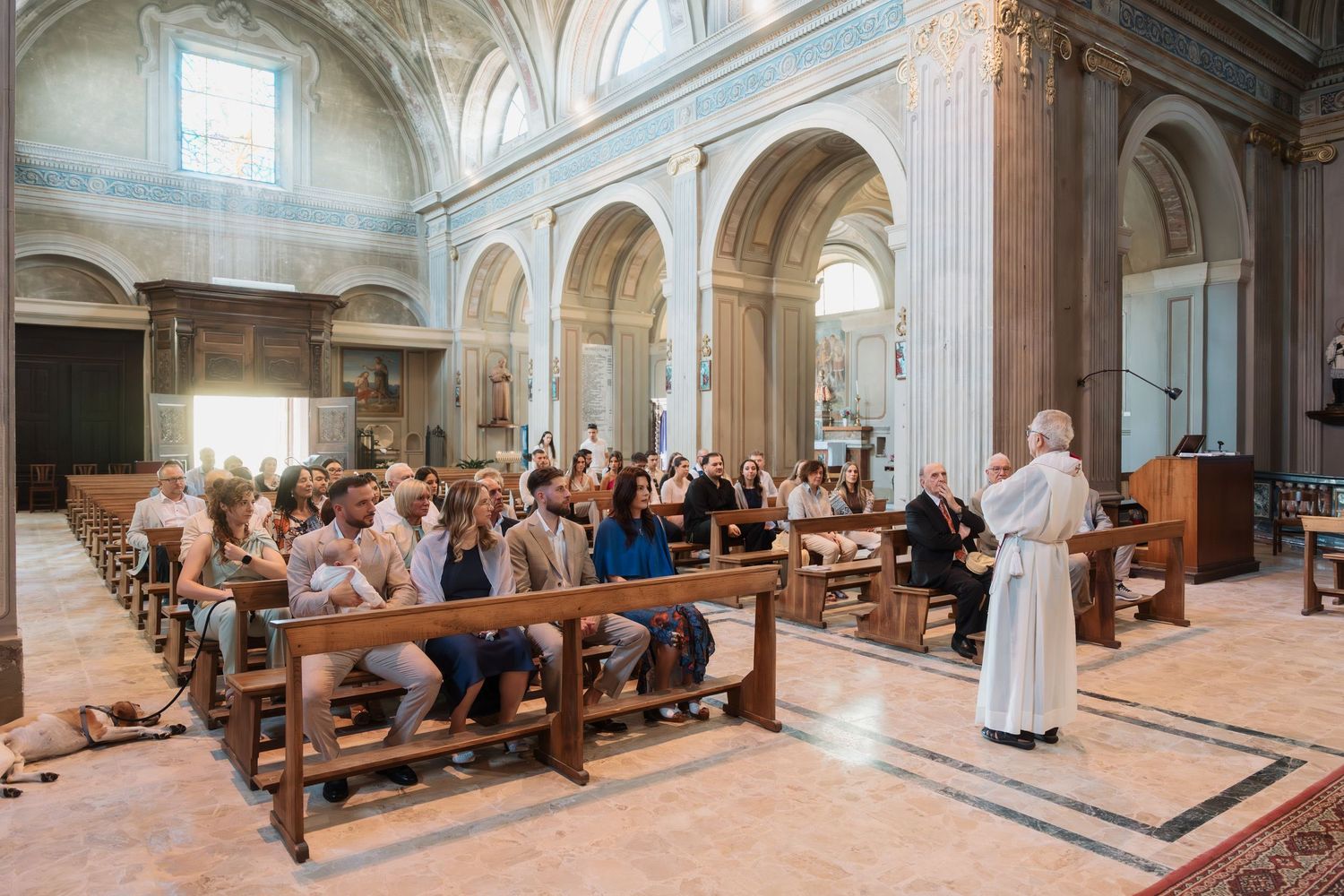 Priest addresses congregation seated in pews during a religious ceremony inside a grand historic church.
