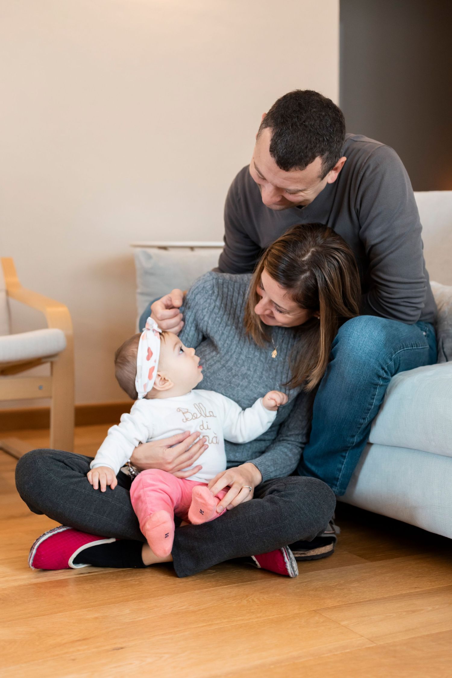 Parents sitting on floor with baby in cozy living room setting.
