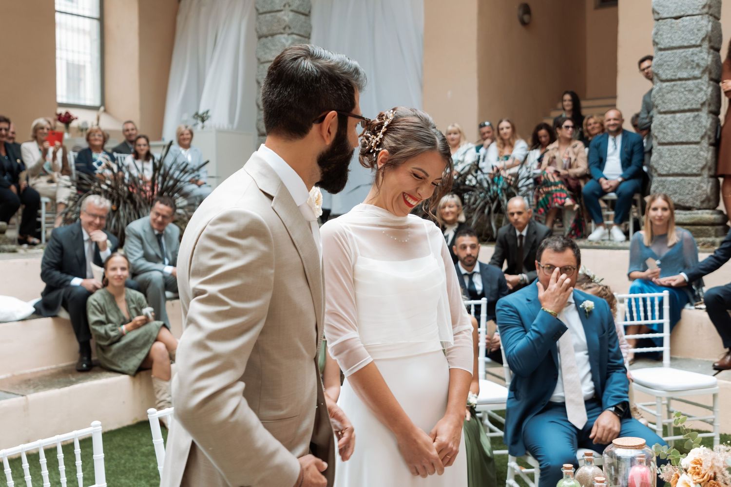 Smiling bride and groom share a joyful moment at the altar during wedding ceremony.