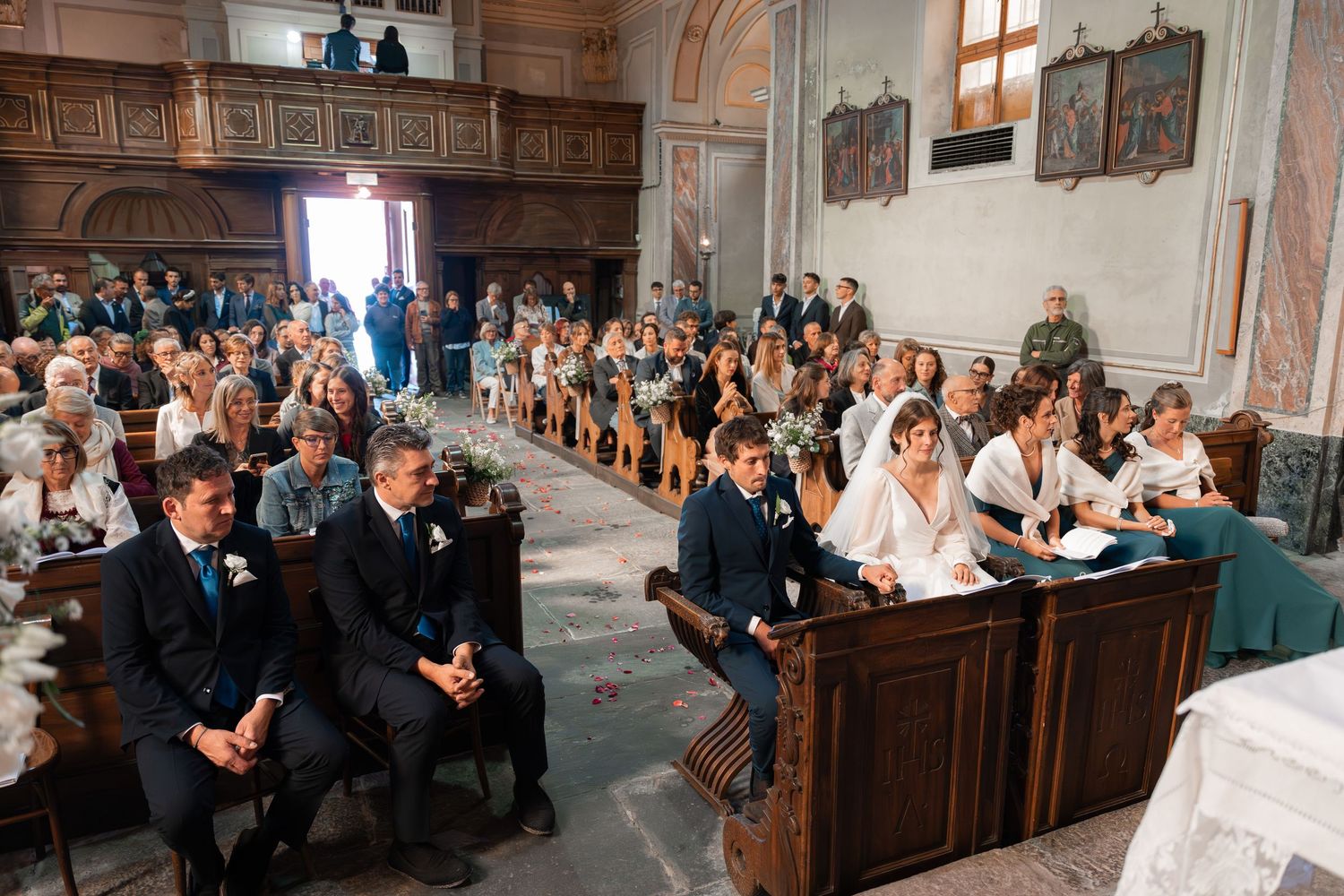 Guests seated in wooden pews during an elegant church wedding ceremony with floral decorations.