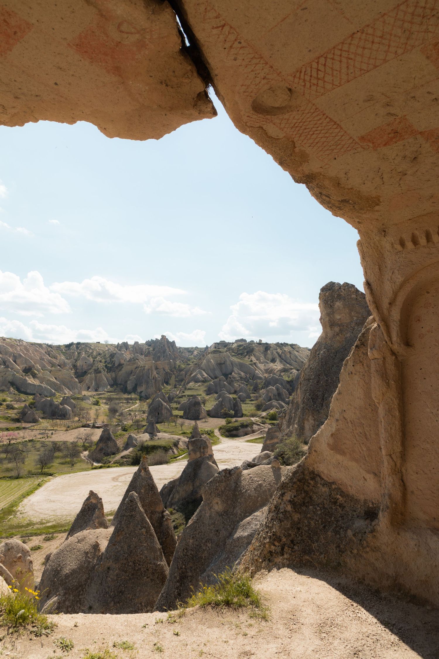 View through an ancient carved cave entrance revealing Cappadocia's unique volcanic rock formations and valley.