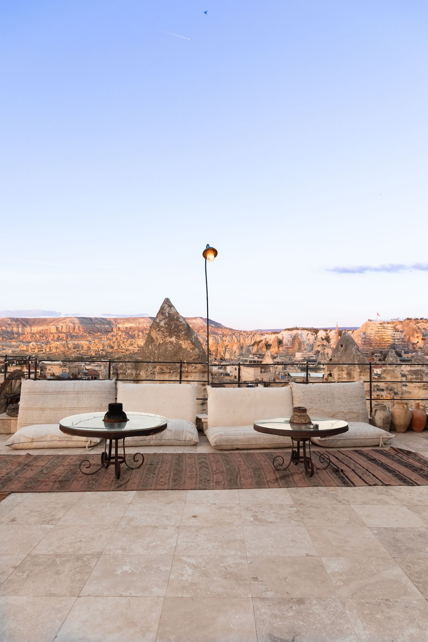 Rooftop terrace with white cushioned seating overlooking the iconic fairy chimney rock formations of Cappadocia.