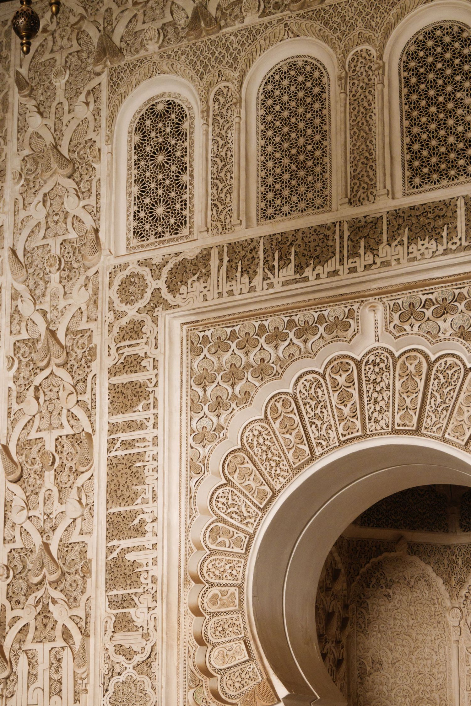 Intricate white plasterwork and geometric carvings on the interior walls of a Moroccan palace.