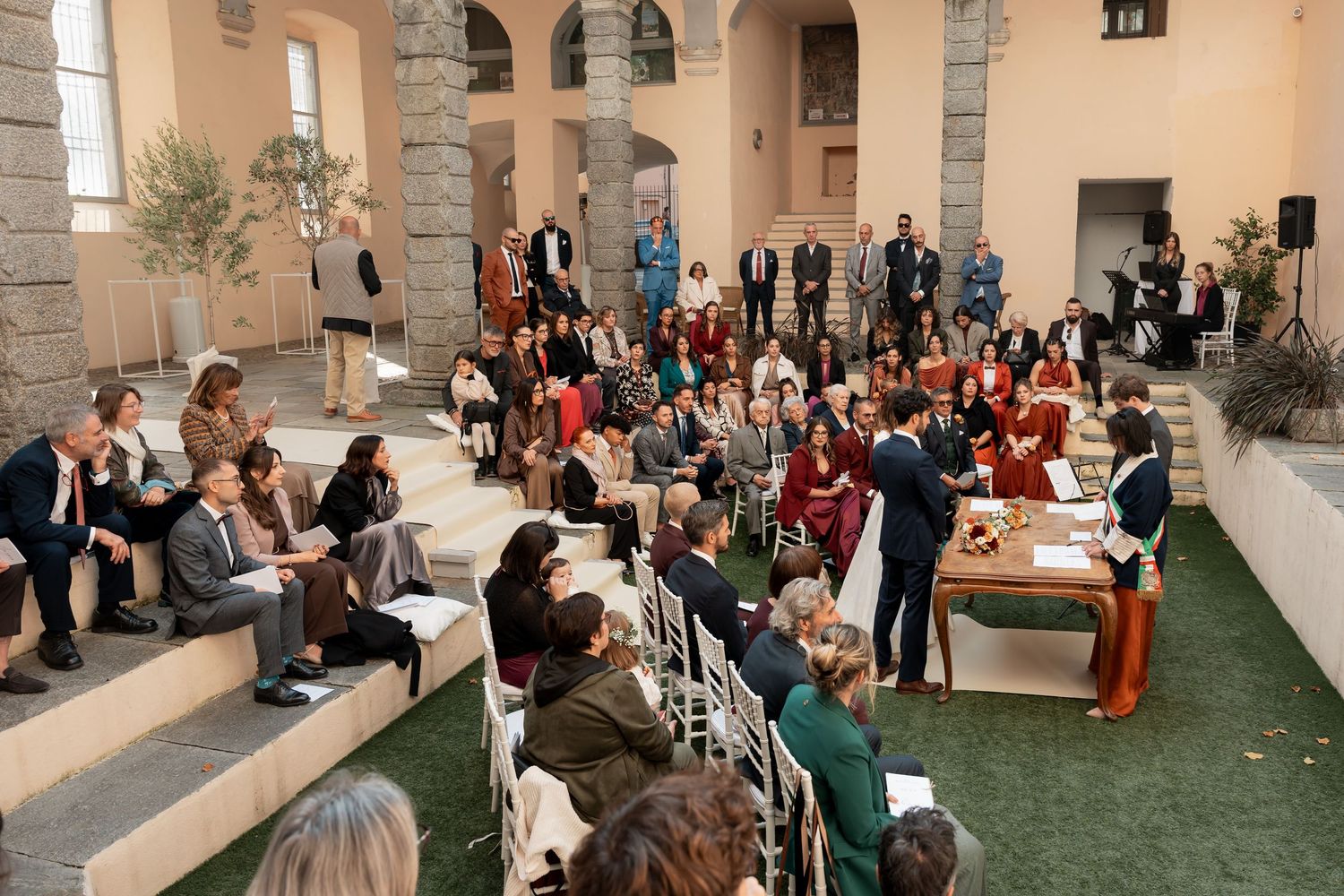 Outdoor wedding ceremony with guests seated in a courtyard of an elegant Italian villa.