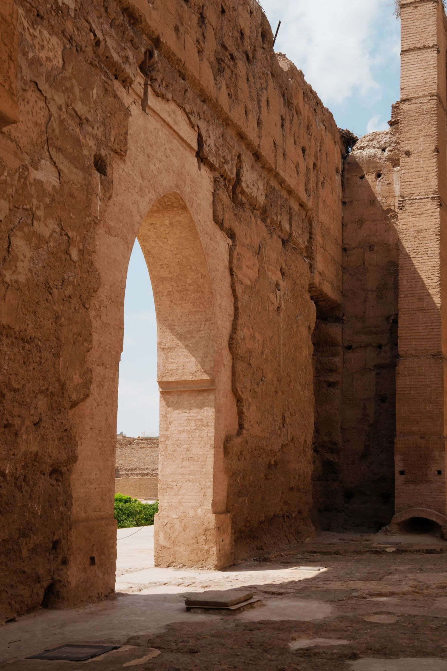 Ancient sandstone arched doorway in the ruins of El Badi Palace under a blue sky in Marrakech.