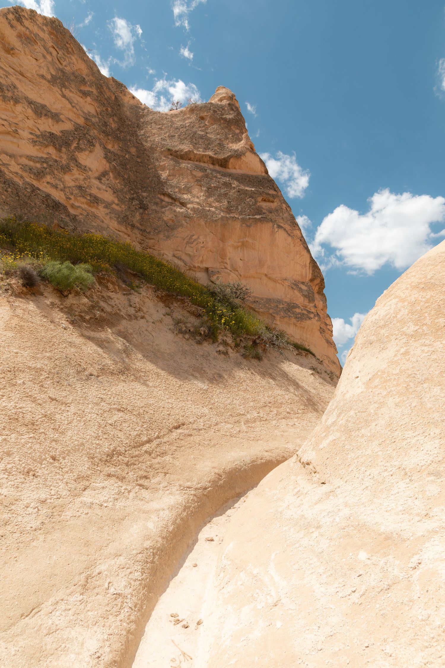 Close-up of contrasting orange and white volcanic rock formations against a blue sky in Cappadocia.