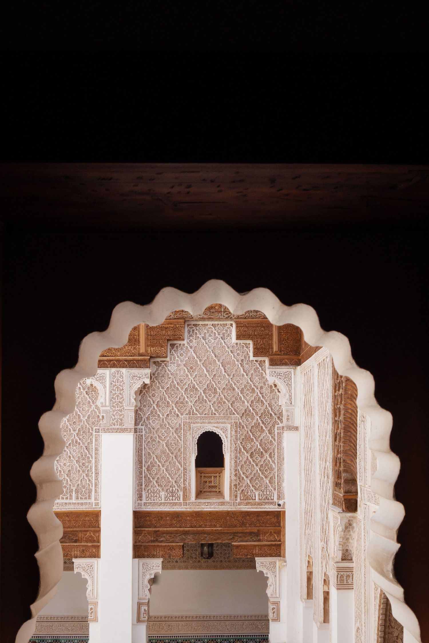 Ornate white Moroccan arch with intricate geometric plasterwork at the Ben Youssef Madrasa.