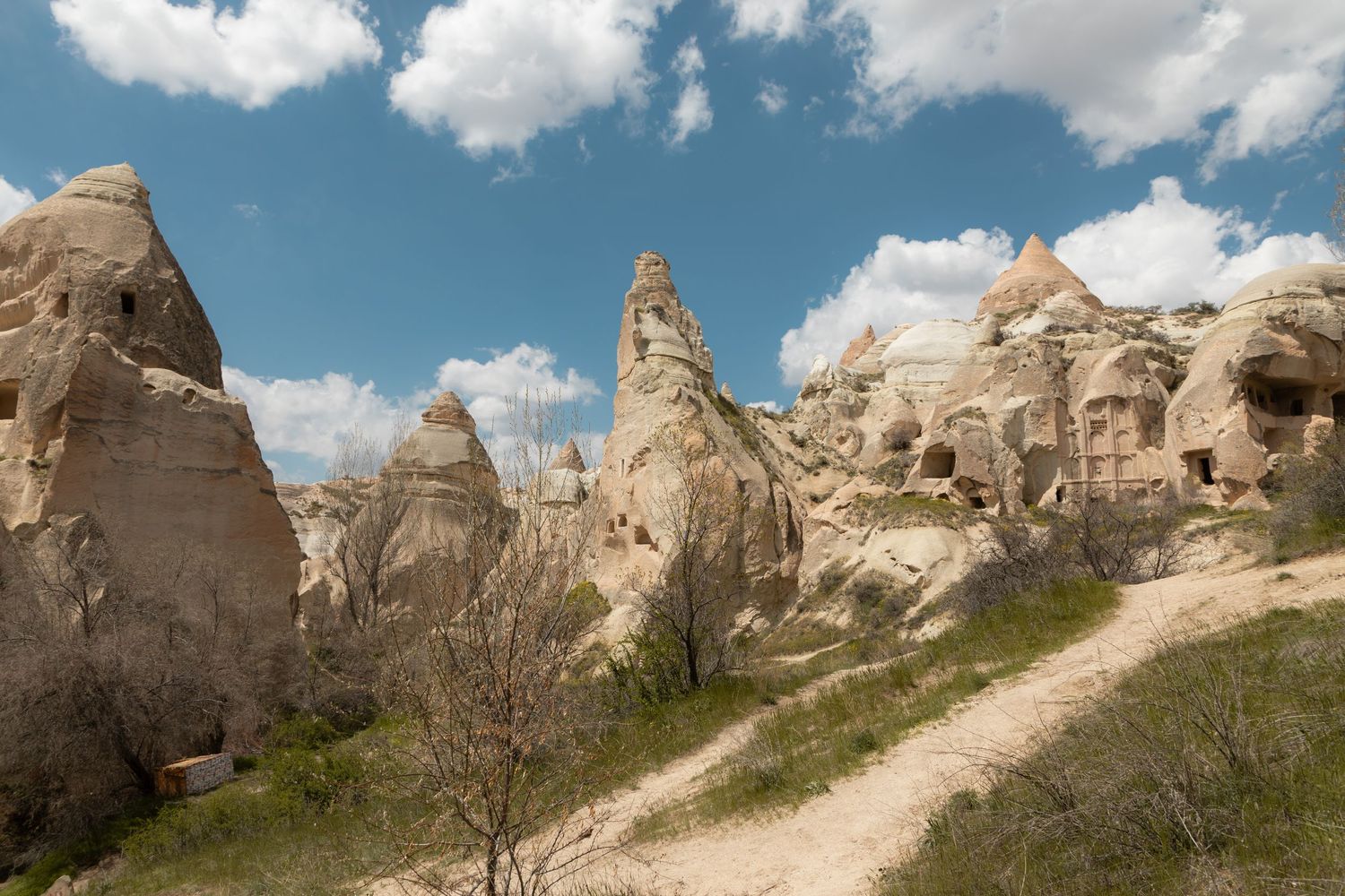 Fairy chimney rock formations and cave homes along a dirt path in Cappadocia, Turkey.